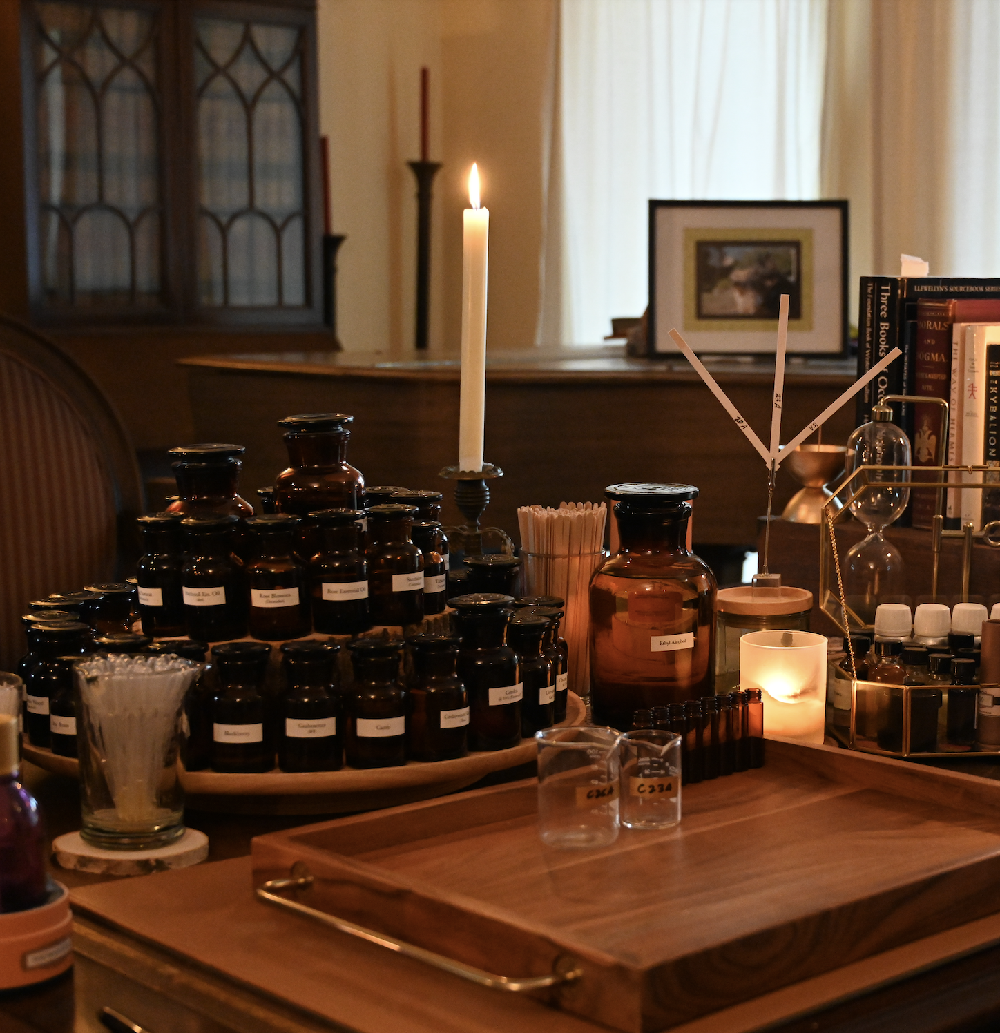 Amber lab bottles of perfume raw materials on wood and leather desk by candlelight