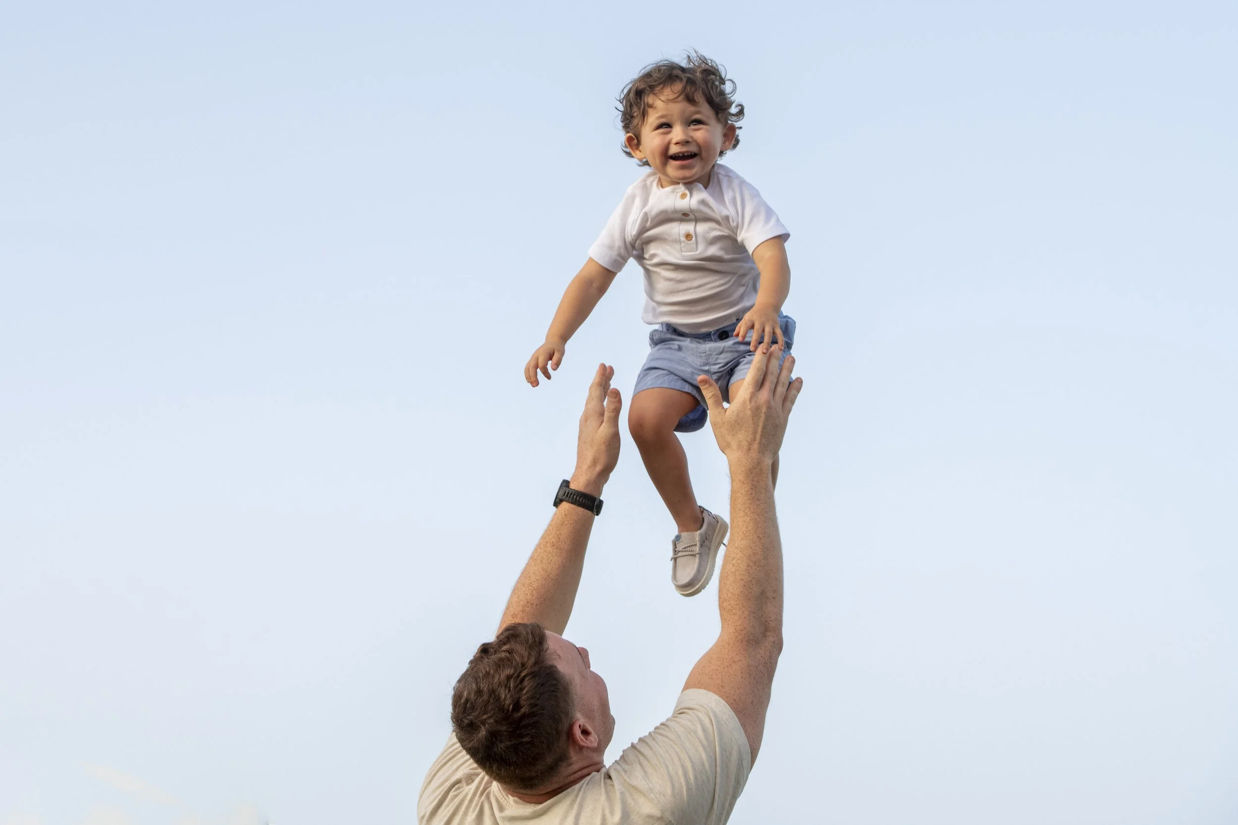 Father tossing his son is the air and having fun at a Family Session at the beach in Boca Raton with Marcu Vanegas Photography