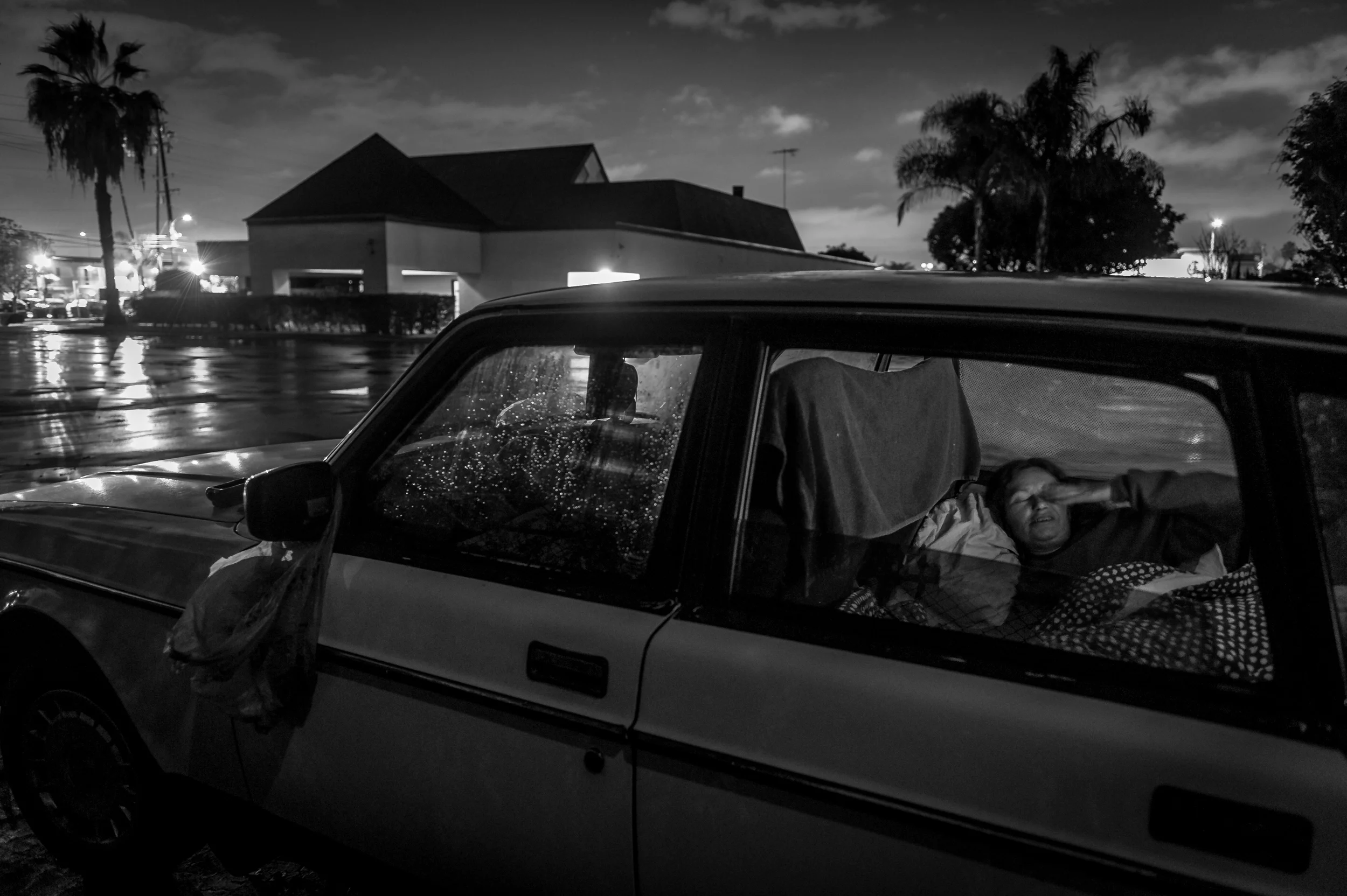 Darlene Matthews shows signs of fatigue after rolling down her window on a rainy evening for a portrait in her car where she has been living for the past three years in Costa Mesa, CA, in the parking lot of a mortuary next to a graveyard. She has been waiting for a housing voucher and benefits from the U.S. Department of Veterans Affairs, (VA). Darlene joined the US Army in 1976; "I was going to join this all women's army and there would be no sexual problems but I joined and there were sexual problems. The whole atmosphere was abusive." She joined the military to escape a chaotic, abusive home life and was forced back into it when she was discharged and has been homeless off and on ever since. "It's like being in a fun house and every door gets slammed in your face every time you try to leave. I feel like giving up sometimes, and nobody would care."