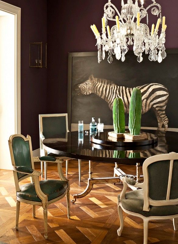 The sophisticated nature of this space calls to me. The eclectic frames of the chairs, all upholstered in different shades of emerald and greens. Love the dark table and the artwork.