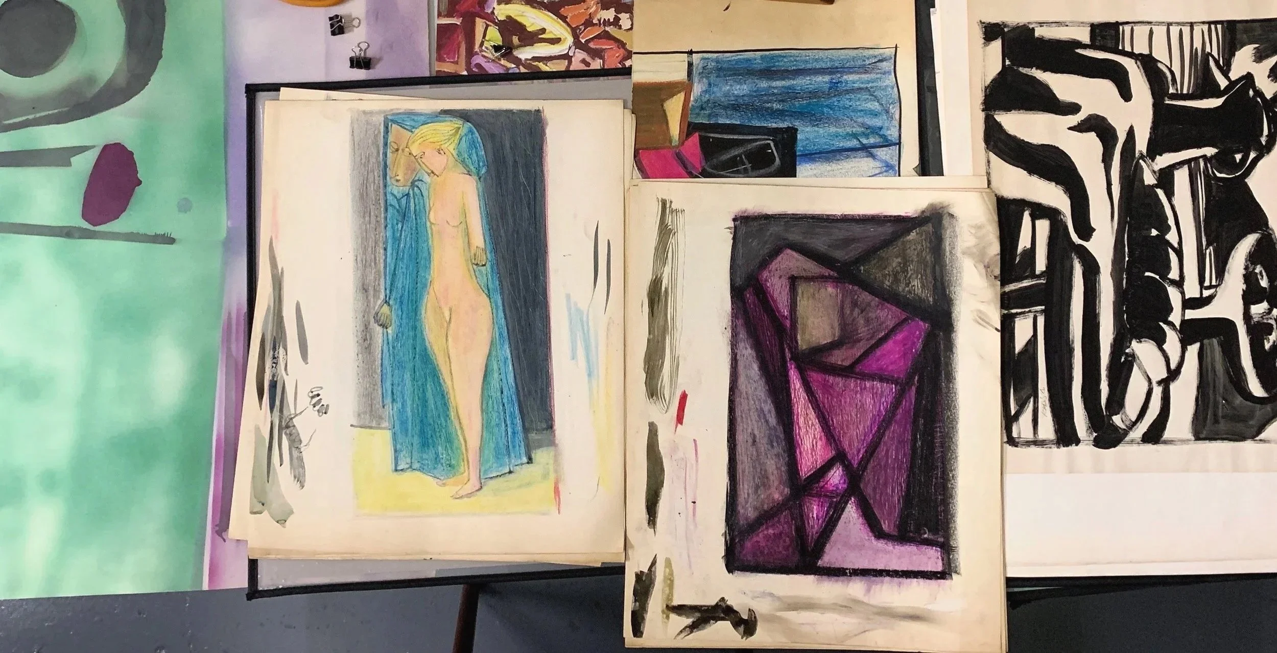 Multiple sketches and paintings of female figures and abstract designs on paper, some colored with markers or crayons, displayed on a surface.