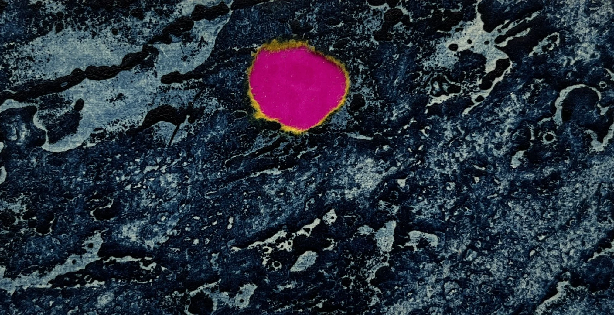 Bright pink and yellow mineral or rock formation on a dark, textured surface.