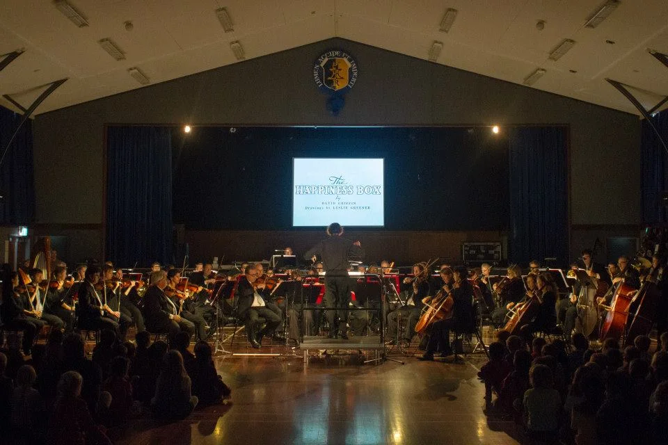 Conductor Hamish McKeich, leading the NZSO in a performance of 'The Happiness Box' at Rongotai College, Wellington, 13 May 2015