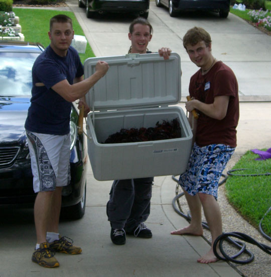   My nephew (left), our son's childhood friend (middle), and our son (right) tote a cooler of live crawfish to the cook. Make special note that our nephew is toting his side one-handed and flexing with his other. LOL.  