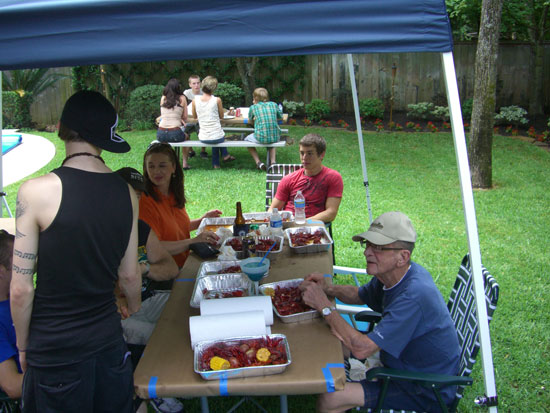   We set up tents and tables in the backyard and serve the crawfish in aluminum tubs. At the table, from left to right: Our youngest son (with his back to us), my brother-in-law's girlfriend, my nephew and Greg's dad. Sitting at the picnic table in t