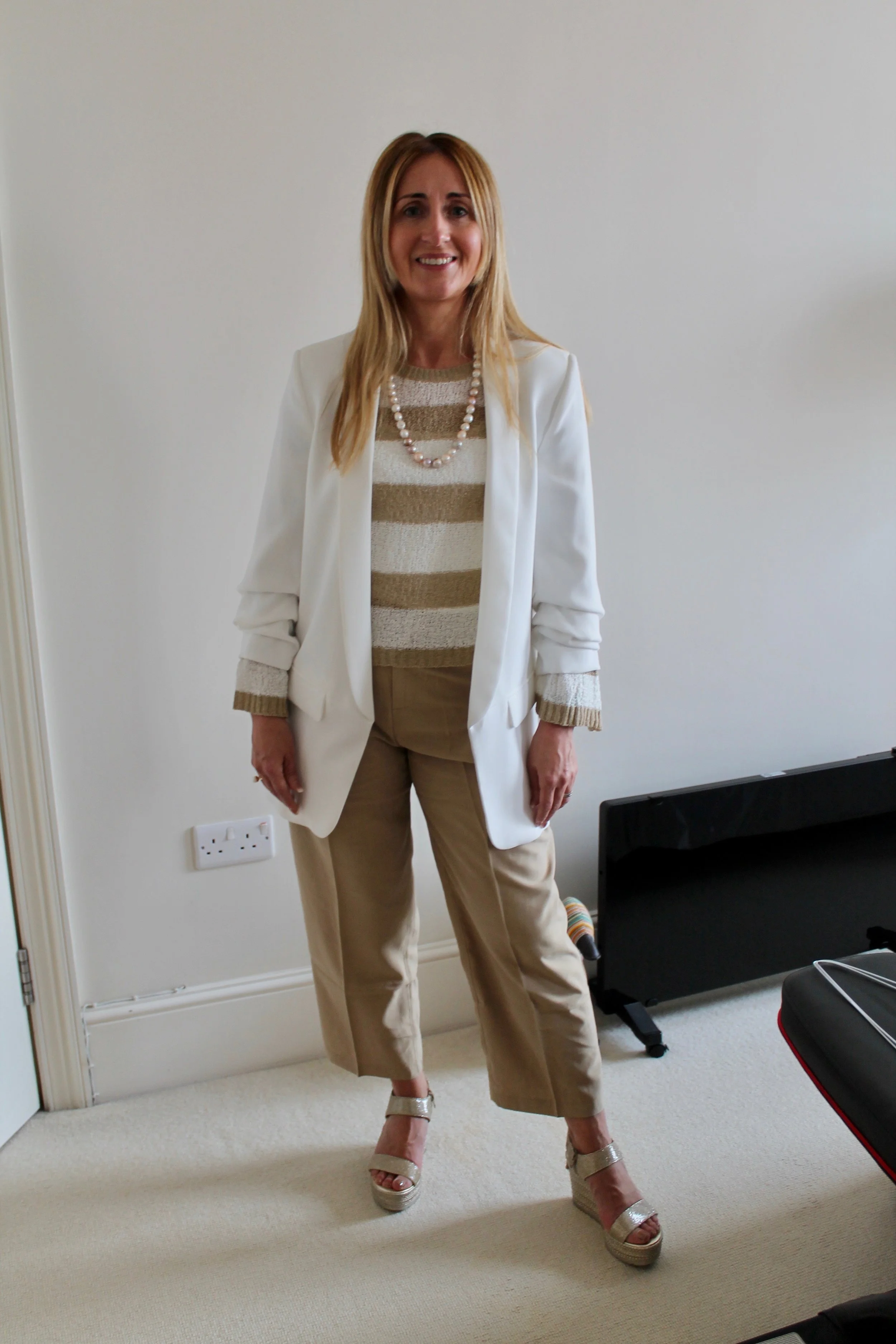 Teaming the white tuxedo over a fine knit and adding pearls and metallic wedges