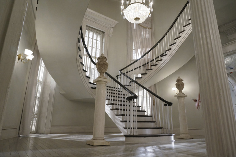On set: By using light walls, flooring, and trim, this enabled production to get the contrast they needed to play against the dark woods in the staircase and antique furniture pieces throughout the rooms.