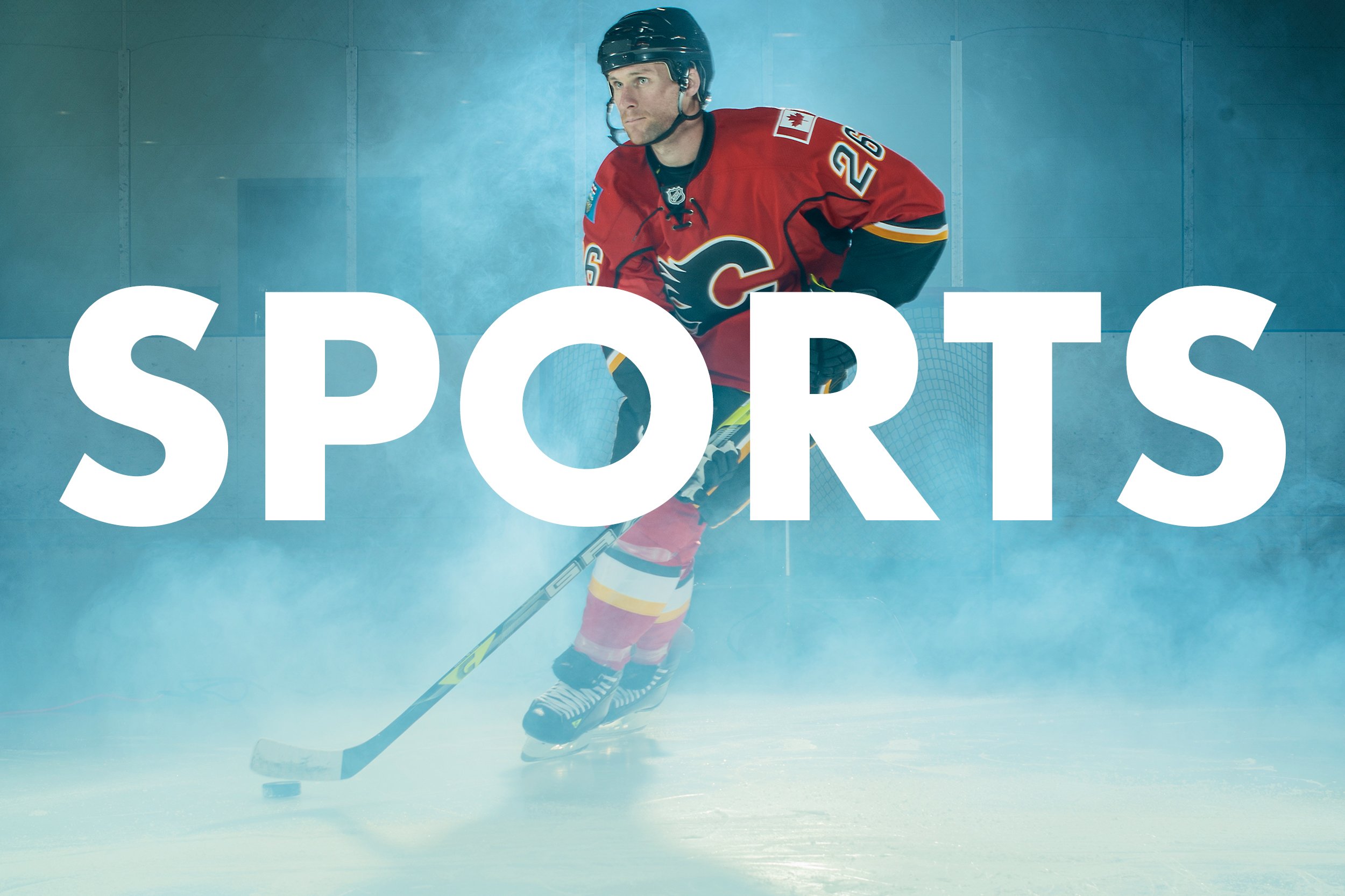 A male ice hockey player in a red jersey and black helmet tips his head forward on the ice, with a hockey stick in his hands, and the word "SPORTS" in large white letters over the lower part of the image.