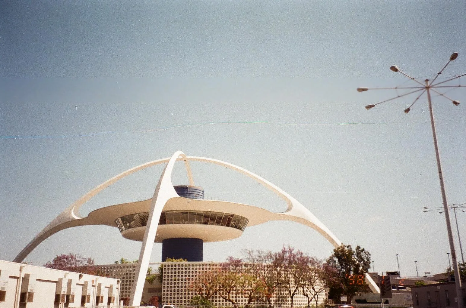 Landmark of the San Francisco skyline, the de Young Museum with distinctive modern architecture in San Francisco, California, with trees and streetlamps in the foreground and a clear sky.