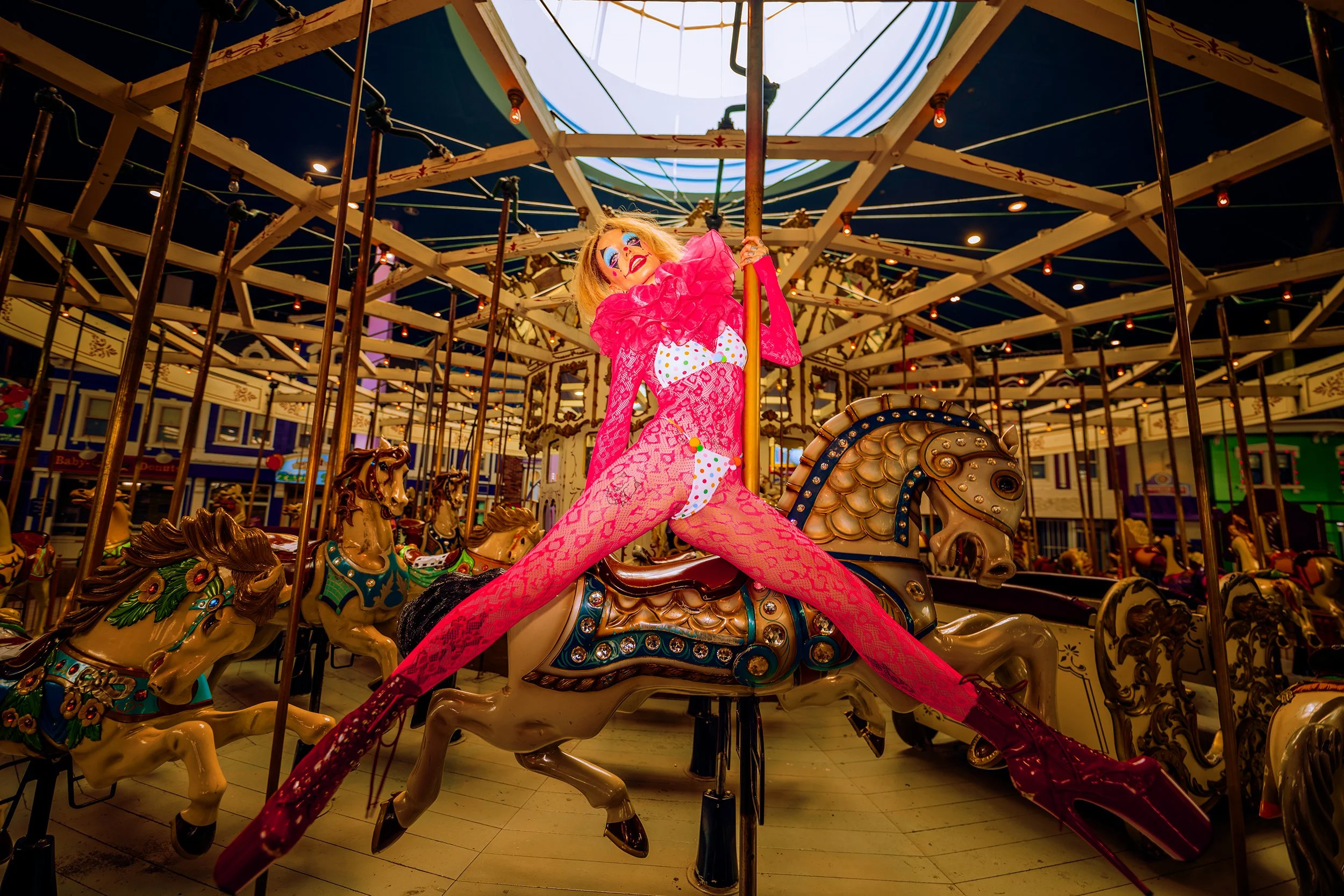 A colorful carousel with a clown riding a horse, located at an amusement park during the evening.