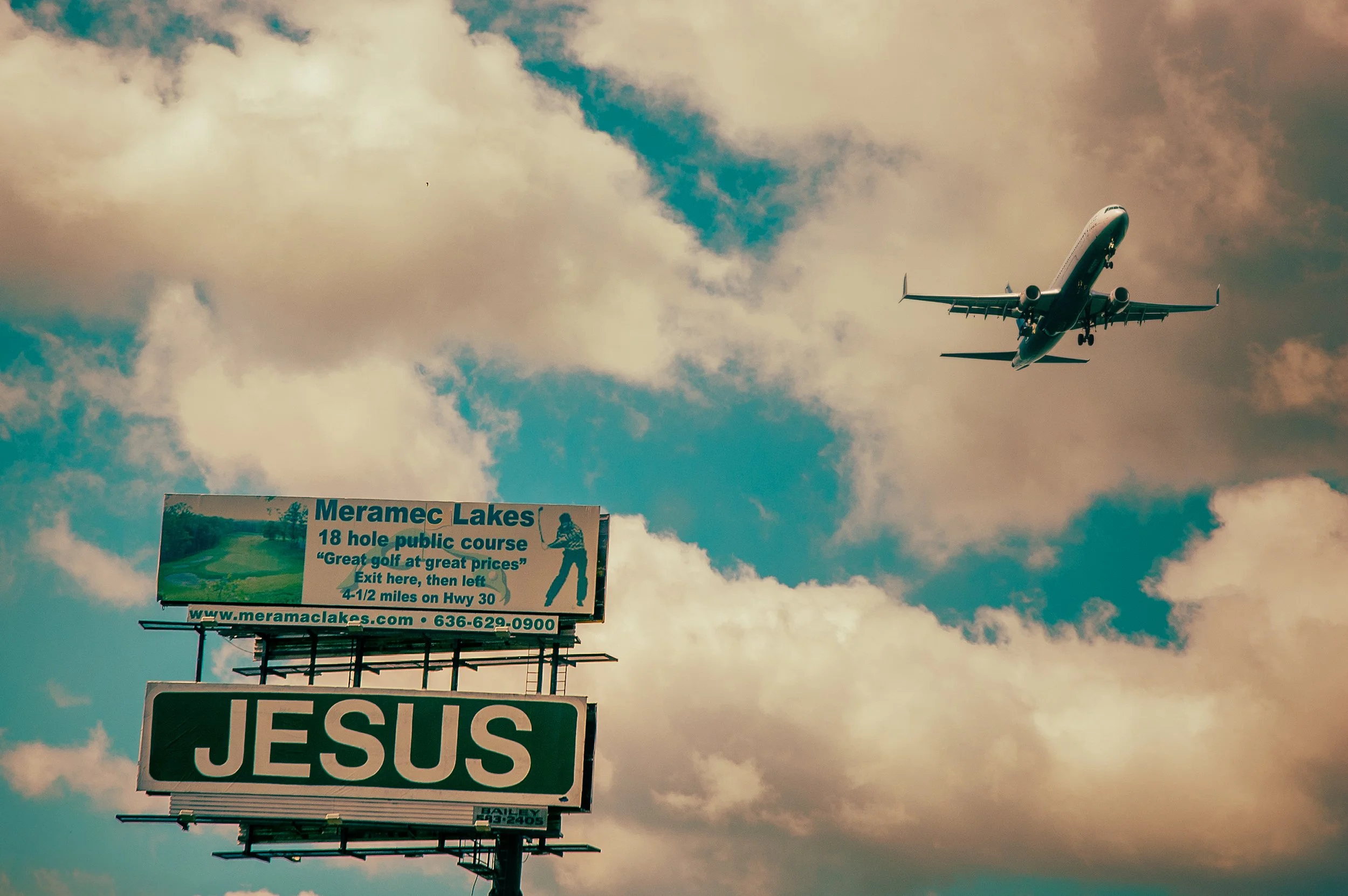 A billboard advertising Meramec Lakes golf course with a sky and airplane in the background.