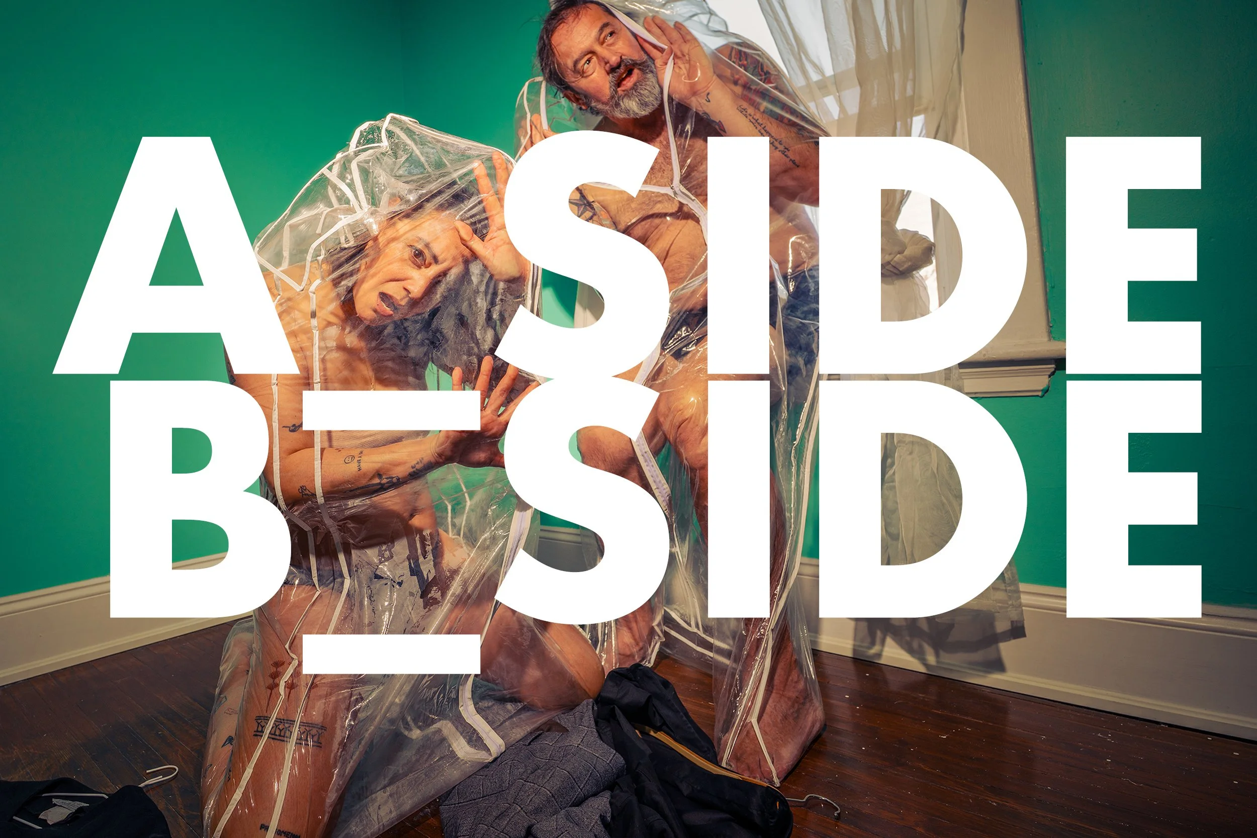 Two naked adults, one male and one female, inside a clear plastic bubble tent in a room with green walls and wooden floor. Large white text overlays the image, reading 'ASIDE' and 'BE'.