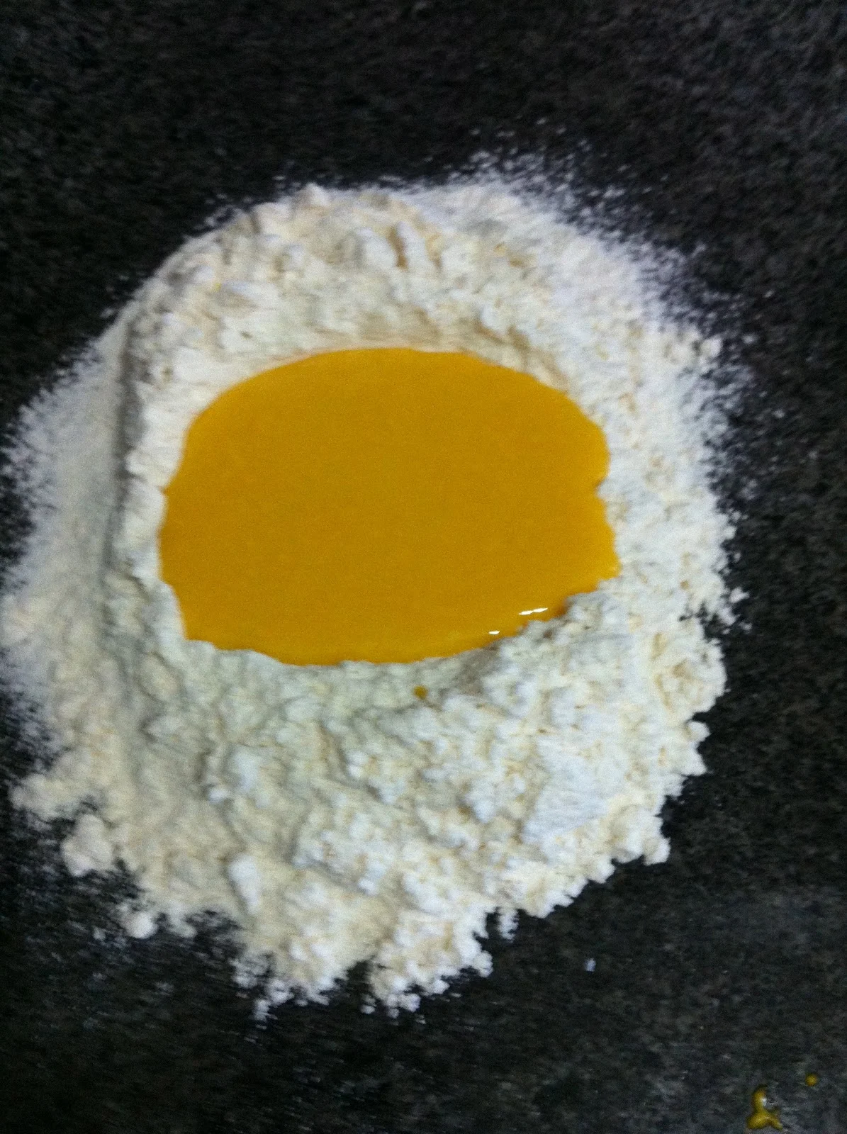 O purê de pequi foi diluído na água e colocado no meio da coroa de farinha de trigo. Primeiro passo para misturar a massa e sová-la até atingir o ponto.
