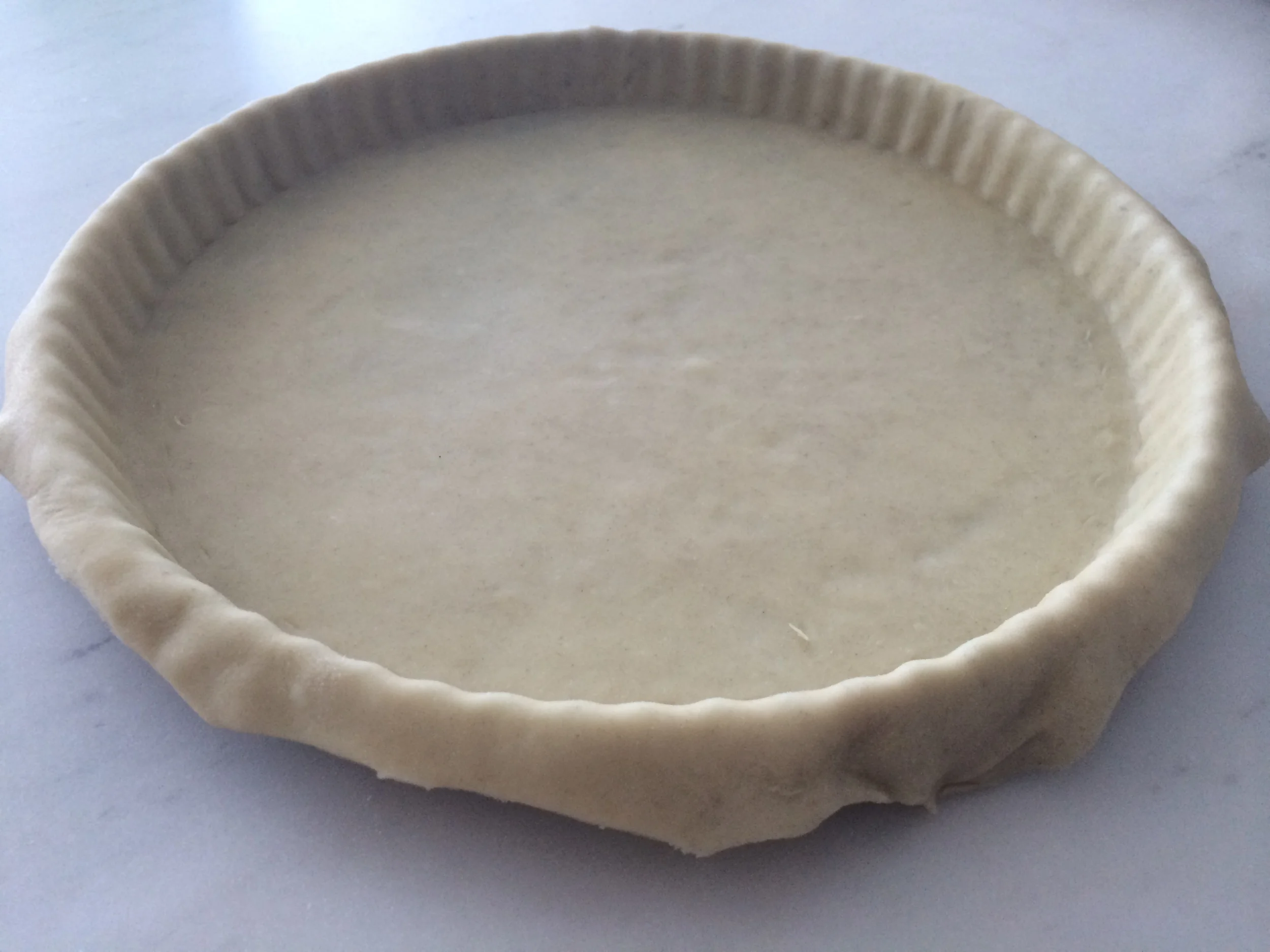 Aos poucos, vá fazendo a massa copiar a forma, com a ajuda das mãos. Corte o excesso de massa que estiver encostando na bancada. Leve-a ao freezer até que congele.