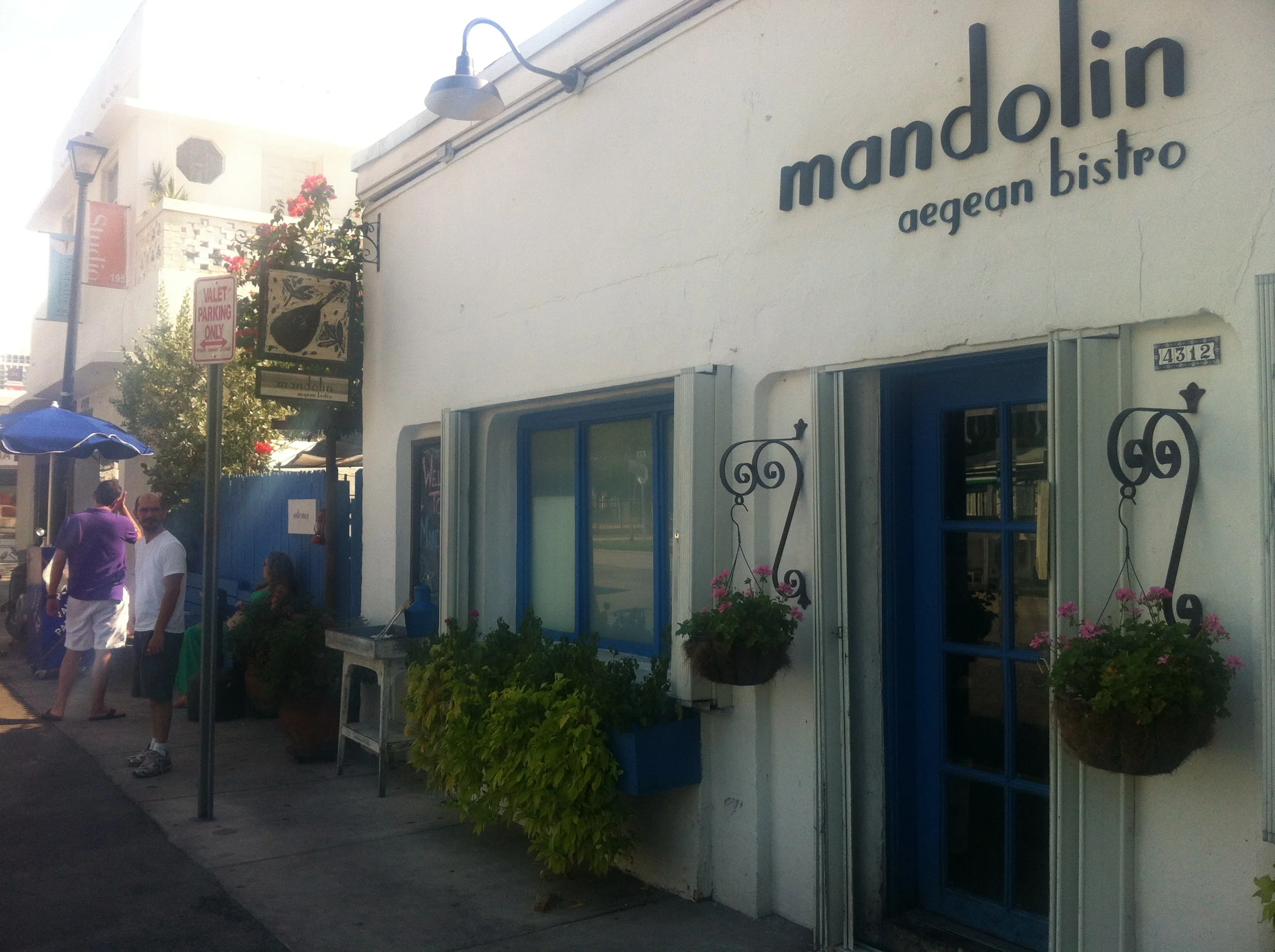 Fachada do restaurante. Ele fica príximo a uma loja de itens de decoração usados e outra de decoração com flores. 