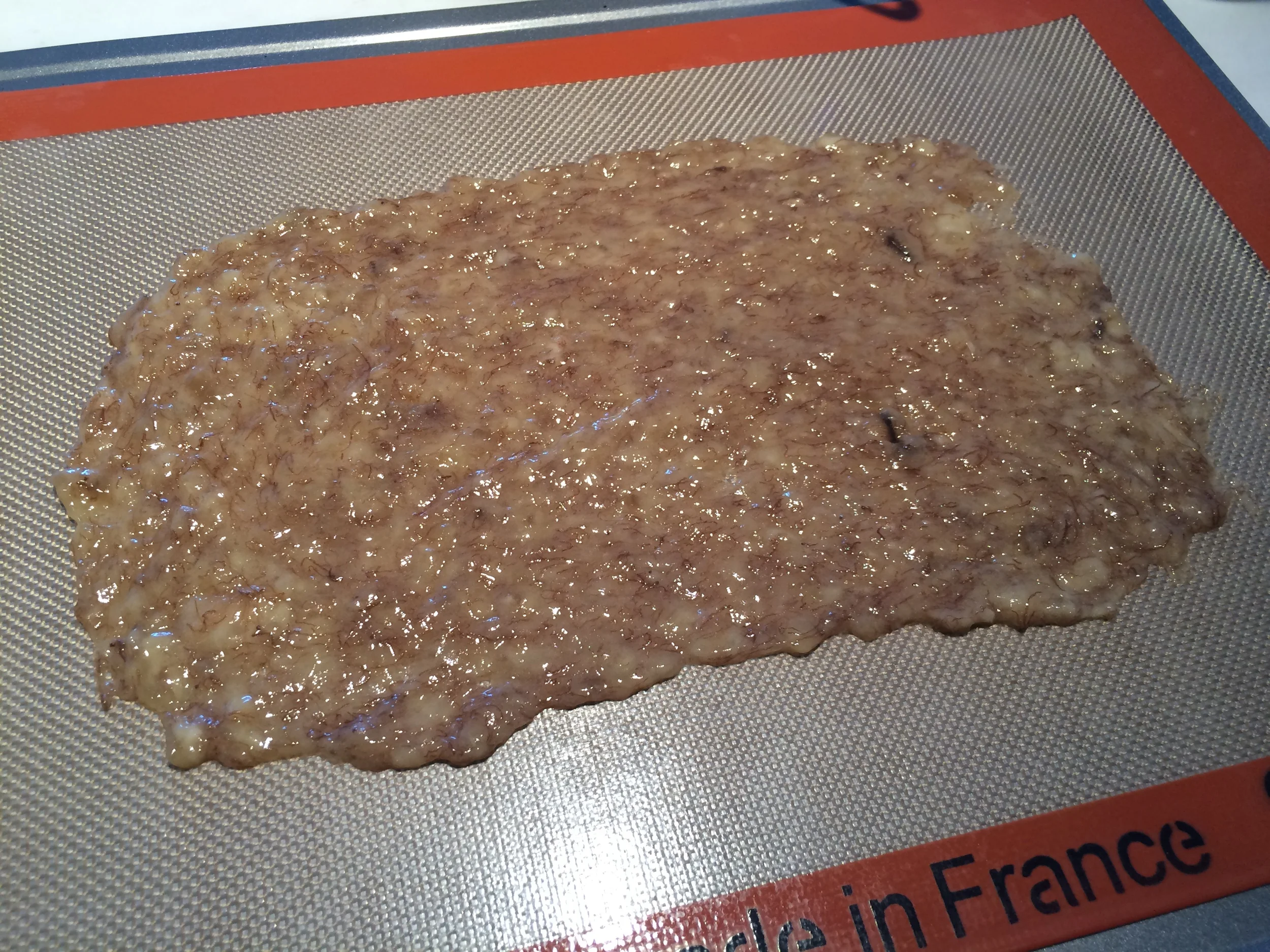 Amasse a banana com um garfo. Destrua qualquer grumo de banana que houver, tornando-a uma pasta lisa. Espalhe-a, com a ajuda de um pão-duro, em um tapete de silicone, até que fique com a espessura de 1 mm. Leve ao forno pré-aquecido a 80 graus Celsius e acompanhe de meia em meia hora. No meu forno, elétrico e muito preciso, levei pouco mais de 3 horas para conseguir o resultado desejado. Num forno à gás pode ser que este tempo seja maior. 