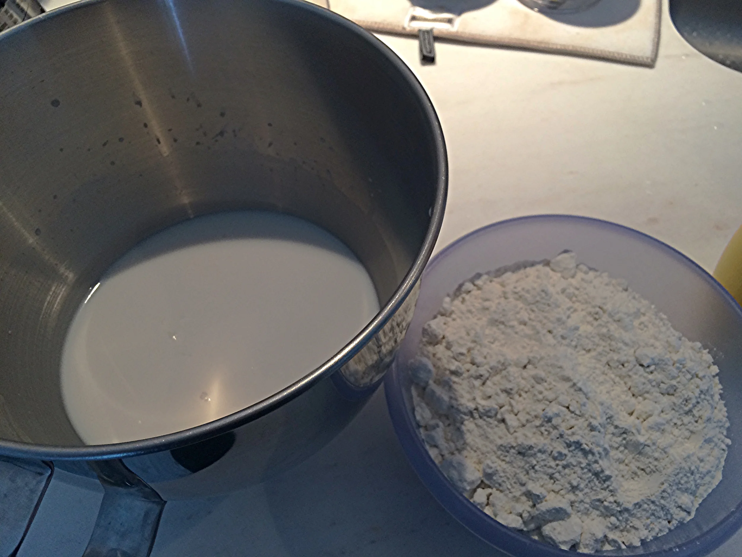 Dissolva o açúcar, o fermento e o leite em pó na água. Misture os demais ingredientes secos à metade da farinha. Acrescente 500g de farinha e leve pra bater na batedeira em velocidade baixa, até incorporar. Acrescente mais 250g de farinha de trigo à massa, que ainda estará muito mole e pegajosa. Aguarde incorporar. Adicione mais 100g e verifique a textura. Eu não precisei usar os 150g restantes aqui, mas usei um pouco da farinha na hora de abrir. acredito que minha massa ficou boa com 900g de farinha*. Adicione a manteiga em pedaços pequenos, até que se dissolvam na massa. 