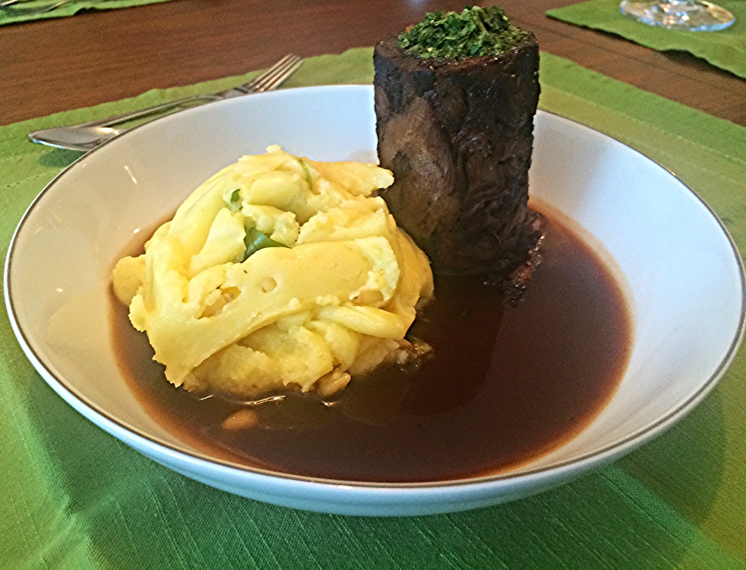 Cordeiro cozido longamente no vinho Malbec, servido no próprio molho de cocção e acompanhado de purê de batatas com pinholi e rúcula. 