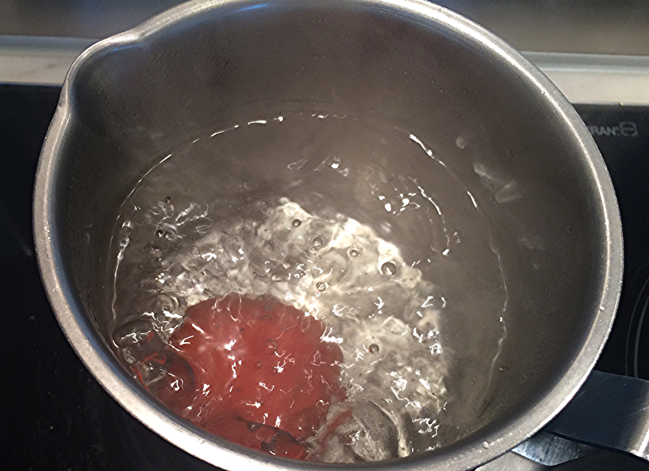 Assim que a água ferver, coloque os tomates na água e deixe-os imersos por 1 minuto ou até que você perceba que a casca começou a se romper e a sair fácil.