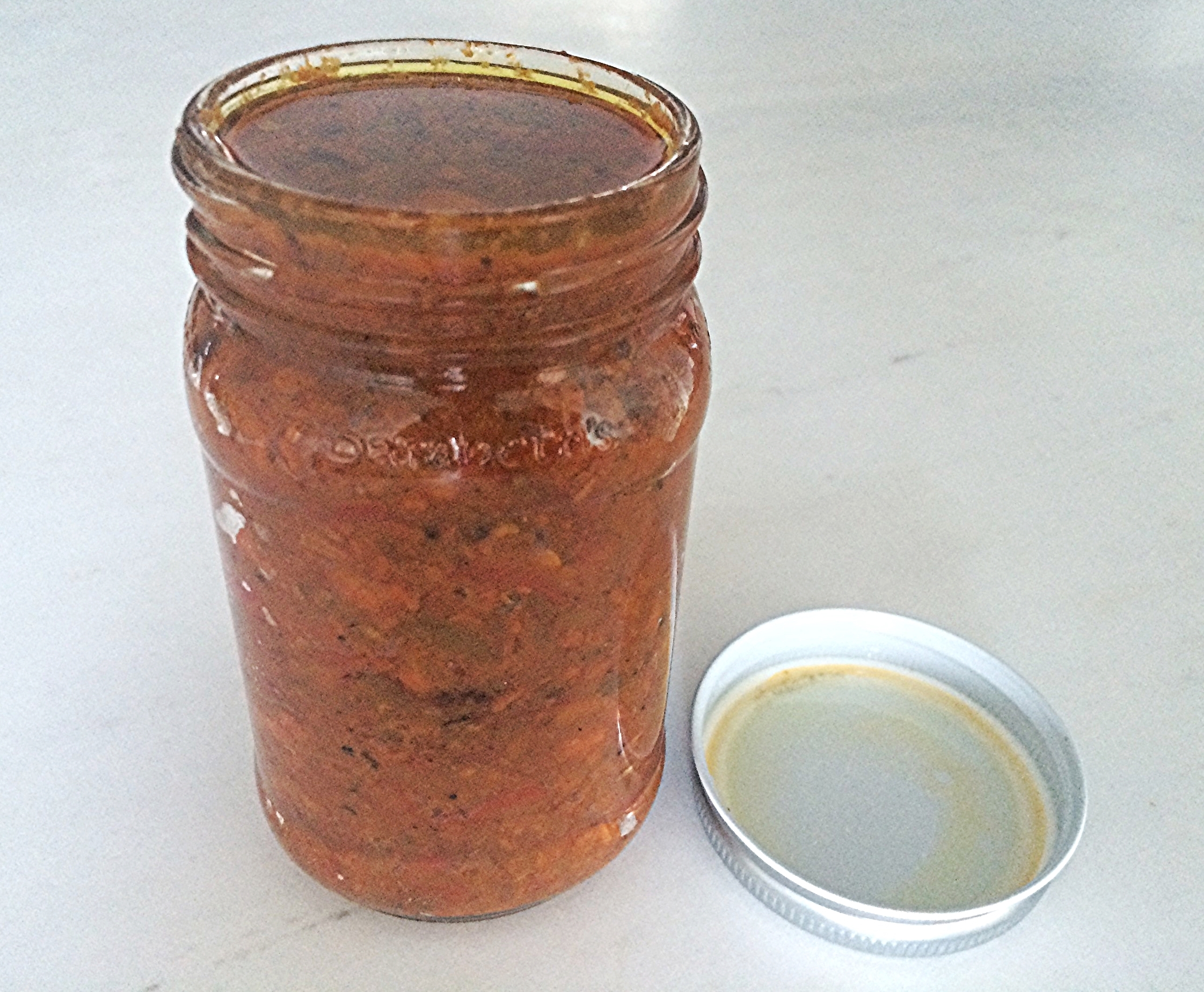Coloque num pote esterilizado com tampa. Dê batidinhas do pote numa superfície dura (coberta com um pano pra amortecer) a cada colherada de pasta que colocar, para que ela assente e elimine ao máximo as bolhas de ar. Ao final, cubra a superfície da massa com azeite extra virgem, tampe e guarde em geladeira. Melhor consumir a partir do dia seguinte e por no máximo, 1 semana. 