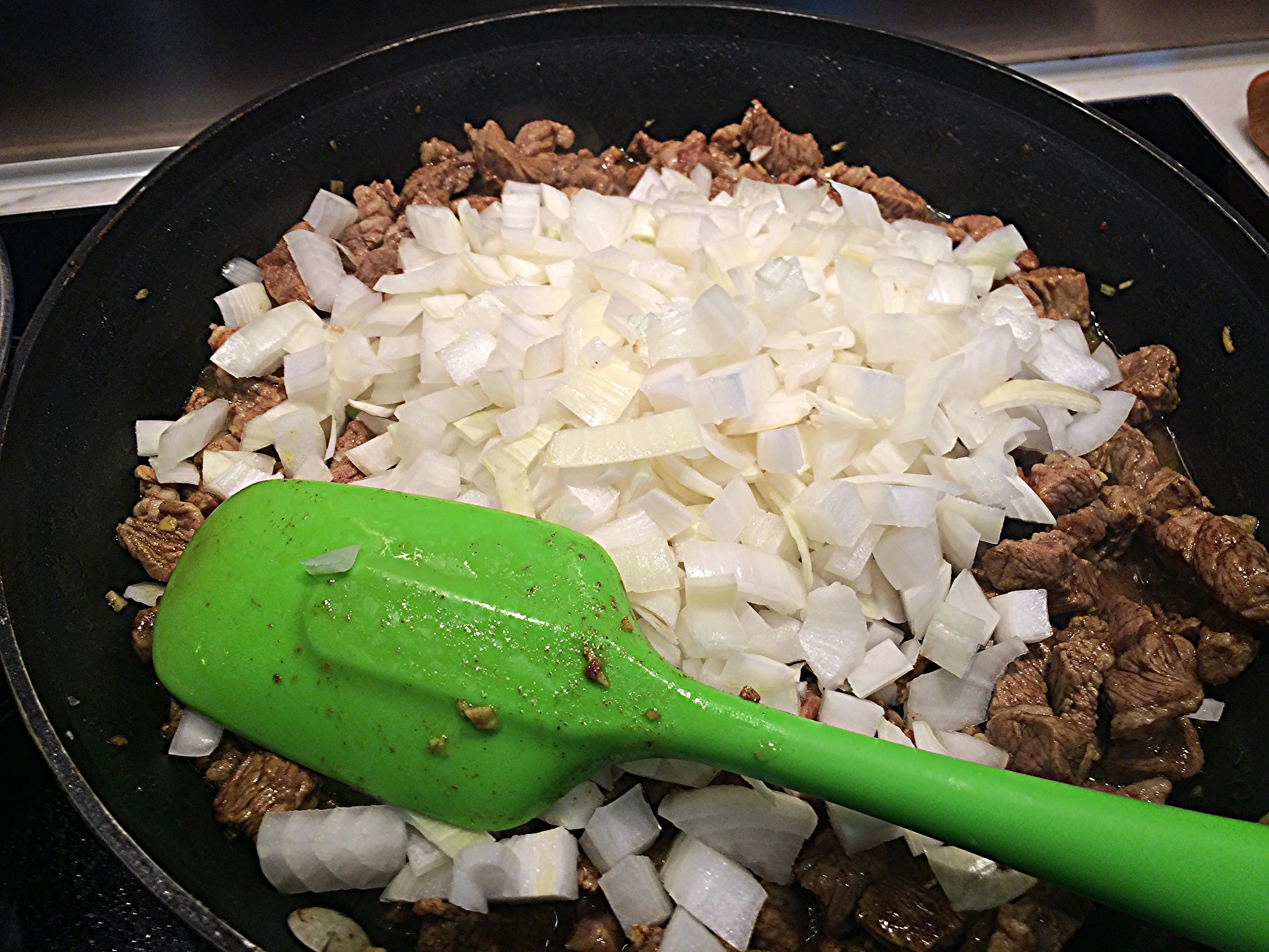 Baixe o fogo. Junte as cebolas e mexa para incorporá-las à carne e envolve-las no tempero. Junte uma pitada de sal e refogue até que as cebolas fiquem transparentes. 