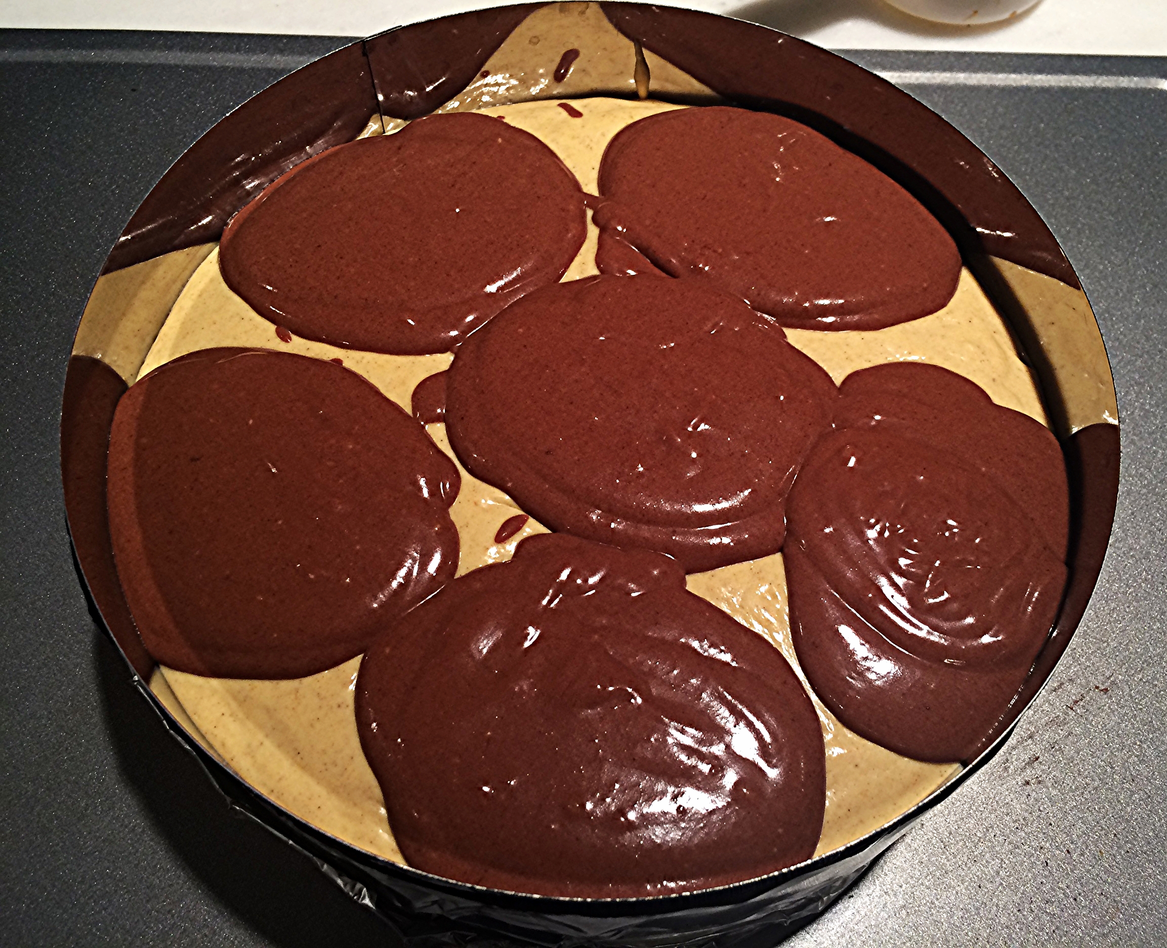 Coloque a massa de abóbora por cima da camada de biscoito, deixando uma quantidade próxima a de uma xícara reservada para fazer o marmorizado. Com uma colher de sopa, distribua a massa de chocolate por cima da de abóbora, como na foto acima. Tá vendo como a quantidade quase tampa a superfície da primeira camada? Foi aqui que eu cometi o meu erro. Se você reservar uma xícara da massa de abóbora pra intercalar com a de chocolate, você vai garantir um resultado próximo ao que obtive da primeira vez que fiz. É só colocá-la com uma colher de sopa, nos intervalos entre uma porção de chocolate e a outra. 