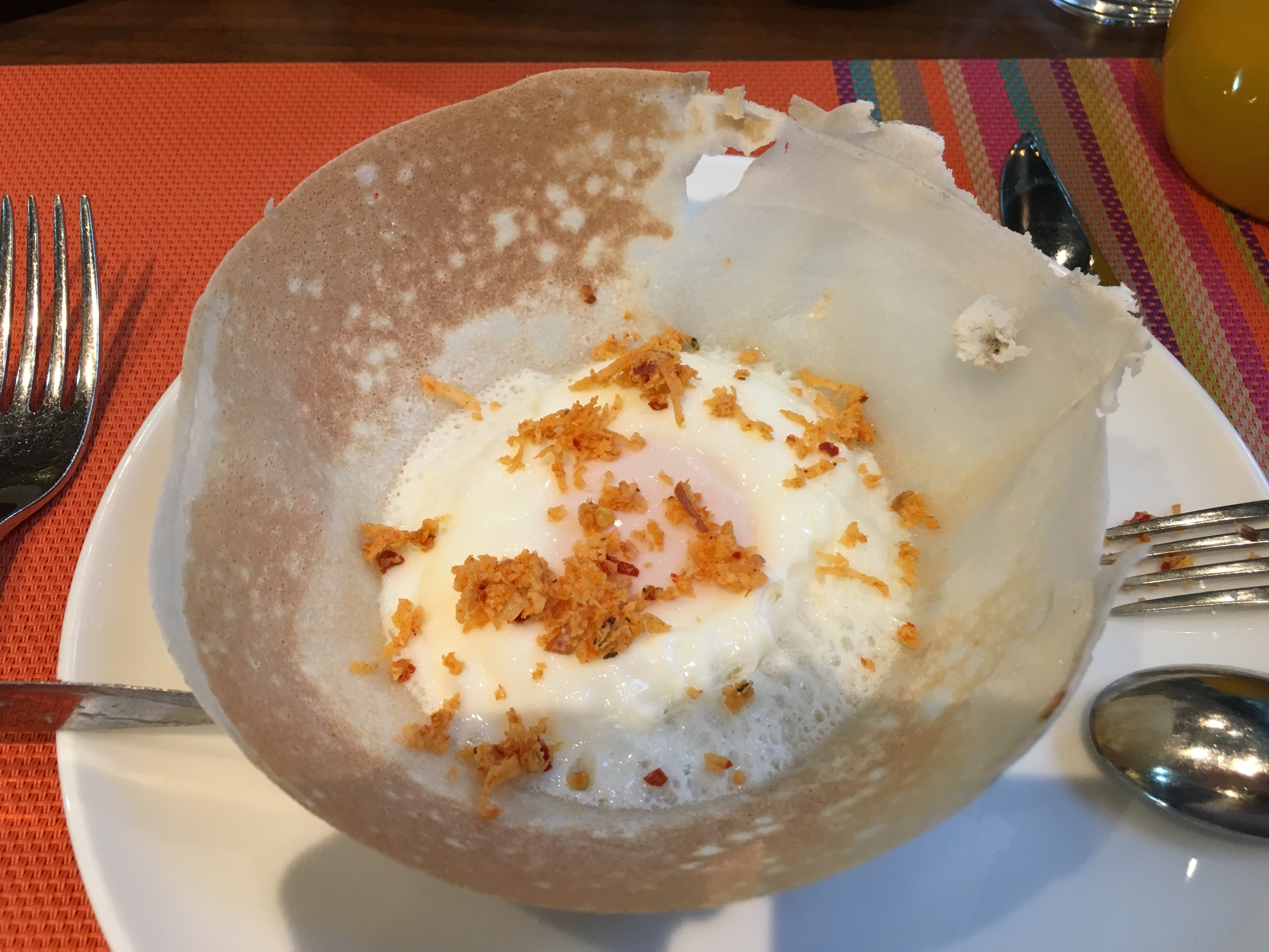 Esse é o Hopper , uma panqueca feita com leite de côco, farinha de arroz e sal, servida com um ovo cozido dentro. Por cima eu espalhei um pouco de Pol Sambol , um condimento de côco ralado com pimenta. Delicioso!