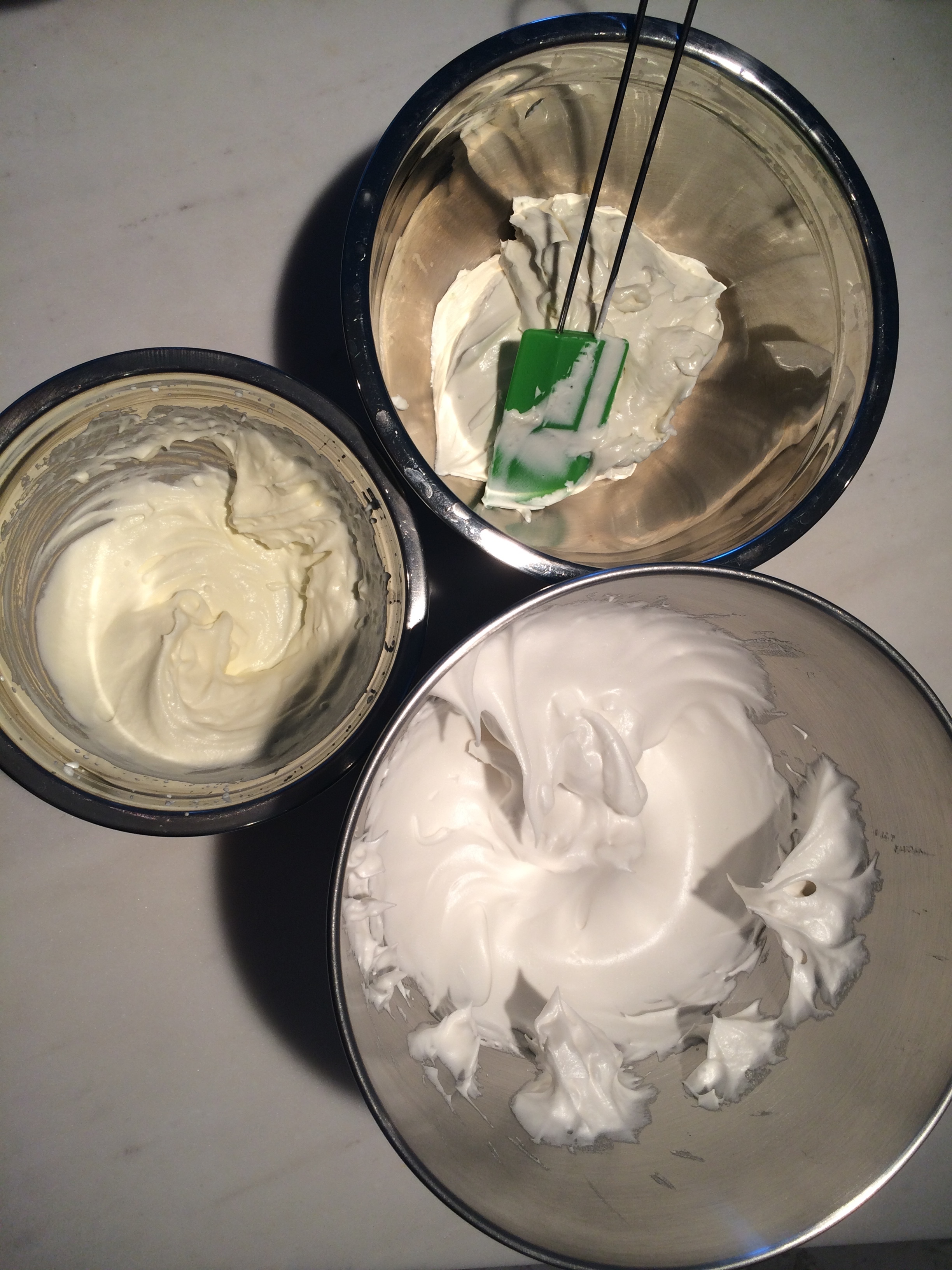 Tudo batido, tenha as três misturas juntas. Verta do chantilly sobre a mistura de cream cheese e misture delicadamente pra incorporar. É importante que o creme de leite esteja batido ao meio ponto, porque se estiver batido ao ponto de servir, virará manteiga quando incorporado ao cream cheese . Depois, junte o merengue suíço e misture novamente até que incorpore. Coloque a massa num saco de confeitar e reserve na geladeira. 