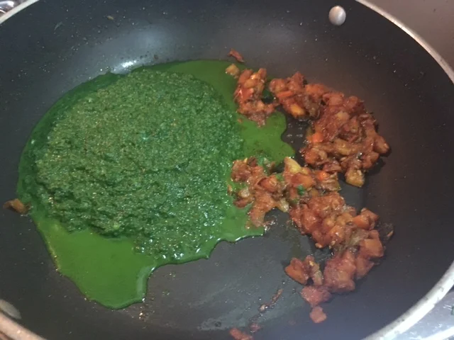 Adicione a pasta processada de espinafre e misture até que incorpore. O espinafre vai ficando amargo e com gosto metálico à medida em que se prolonga seu cozimento. Depois de acrescentá-lo você precisa finalizar o prato rapidamente para evitar que isso aconteça. Adicione o creme de leite e misture para incorporá-lo. Prove e ajuste o sal. Se por acaso você achar que o amargor já começou a aparecer, umas gotas de limão ajudam a ajustar o sabor. Junte os cubos de paneer ao molho, reservando alguns deles para servir por cima. 