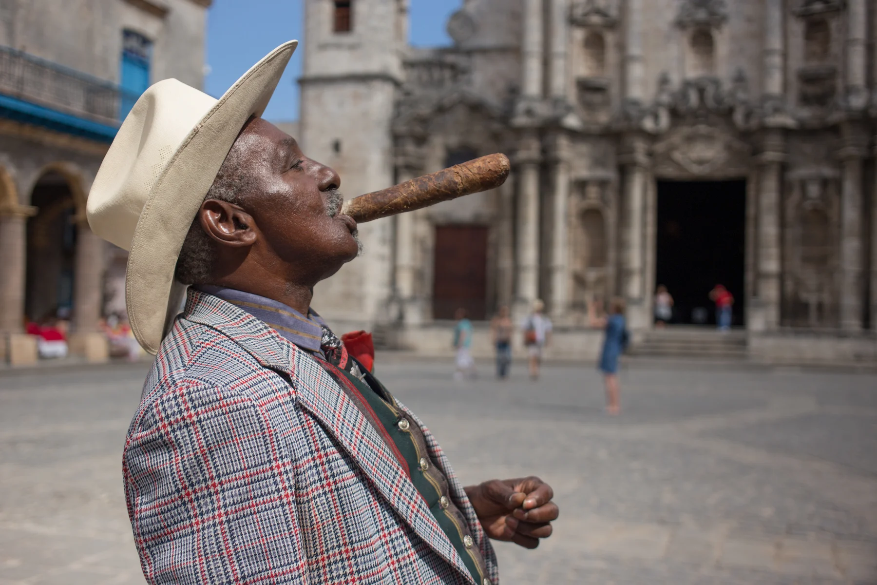 Cuban street preformer with oversized cigar in Havana's Cathedral Square.