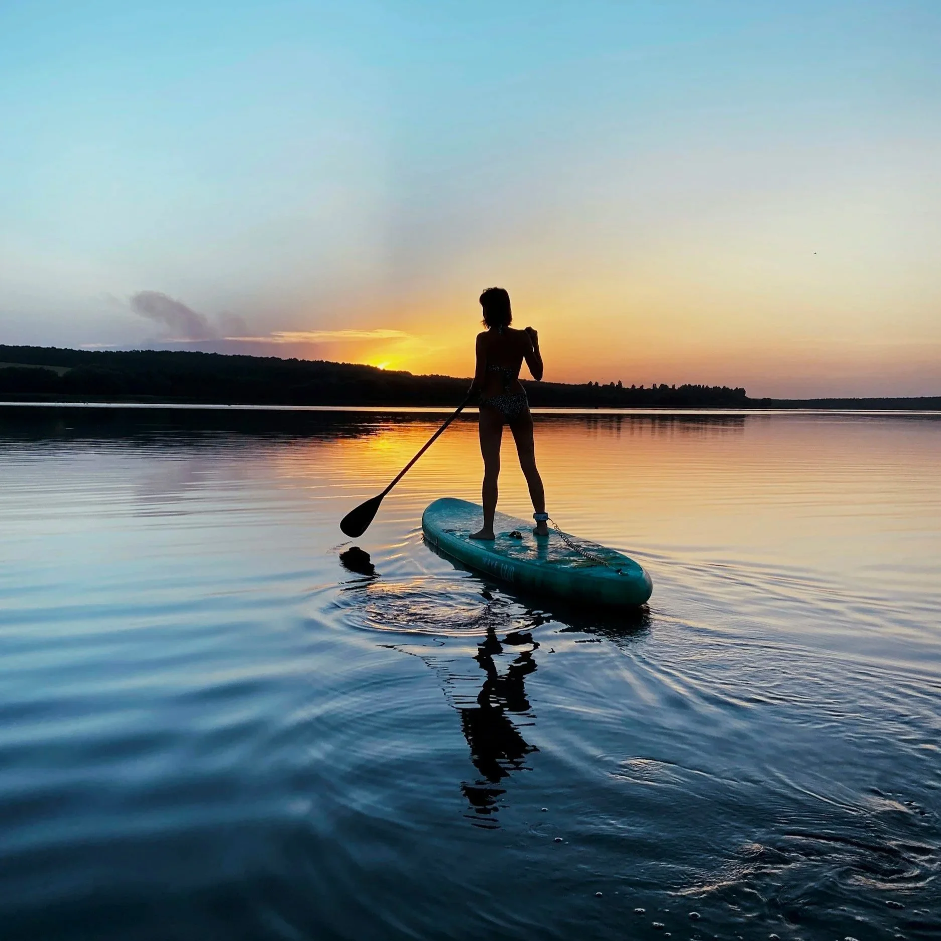 Person stand up paddle boarding on Lake with mountain views