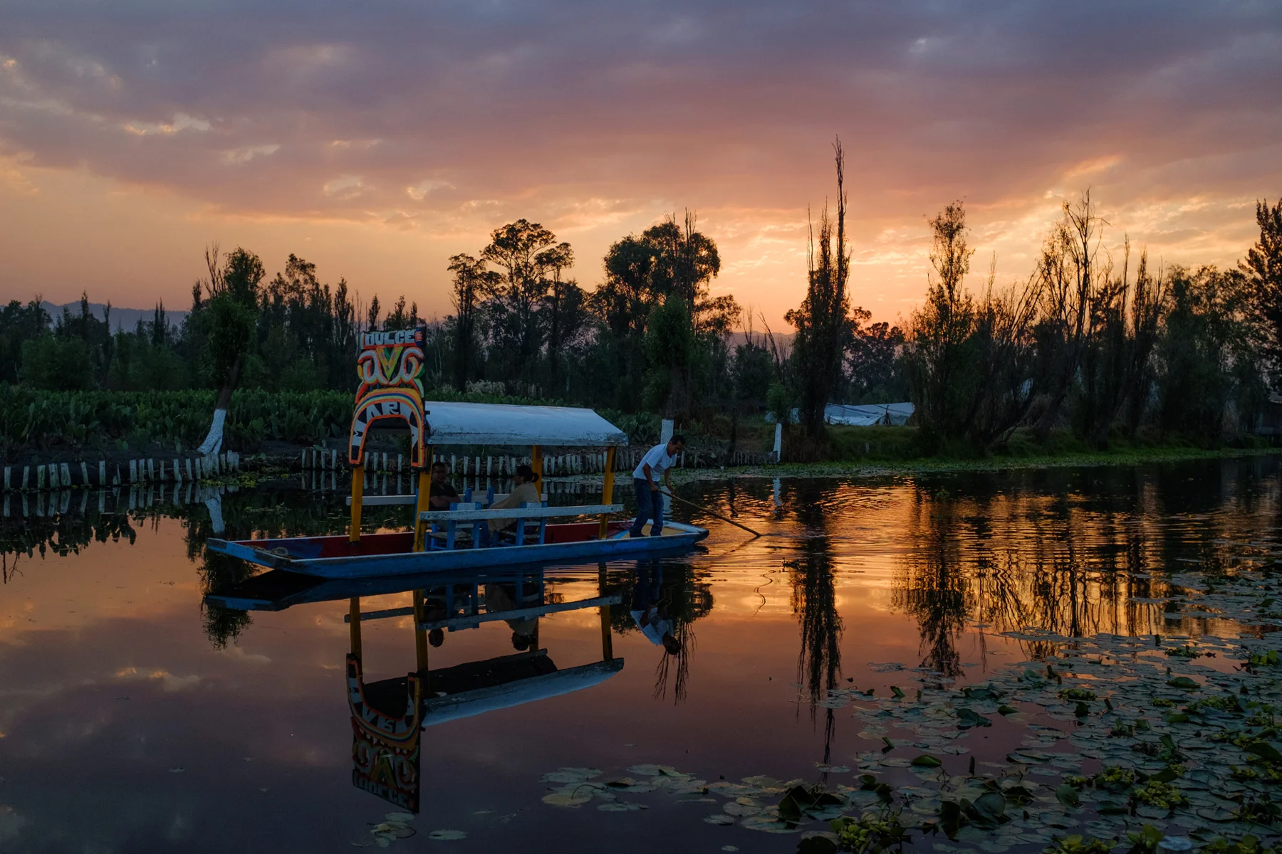 March 3, 2018 - Mexico City, Mexico: A trajinera floats by at sunset in Xochimilco. (GOOD Magazine/Mallika Vora)