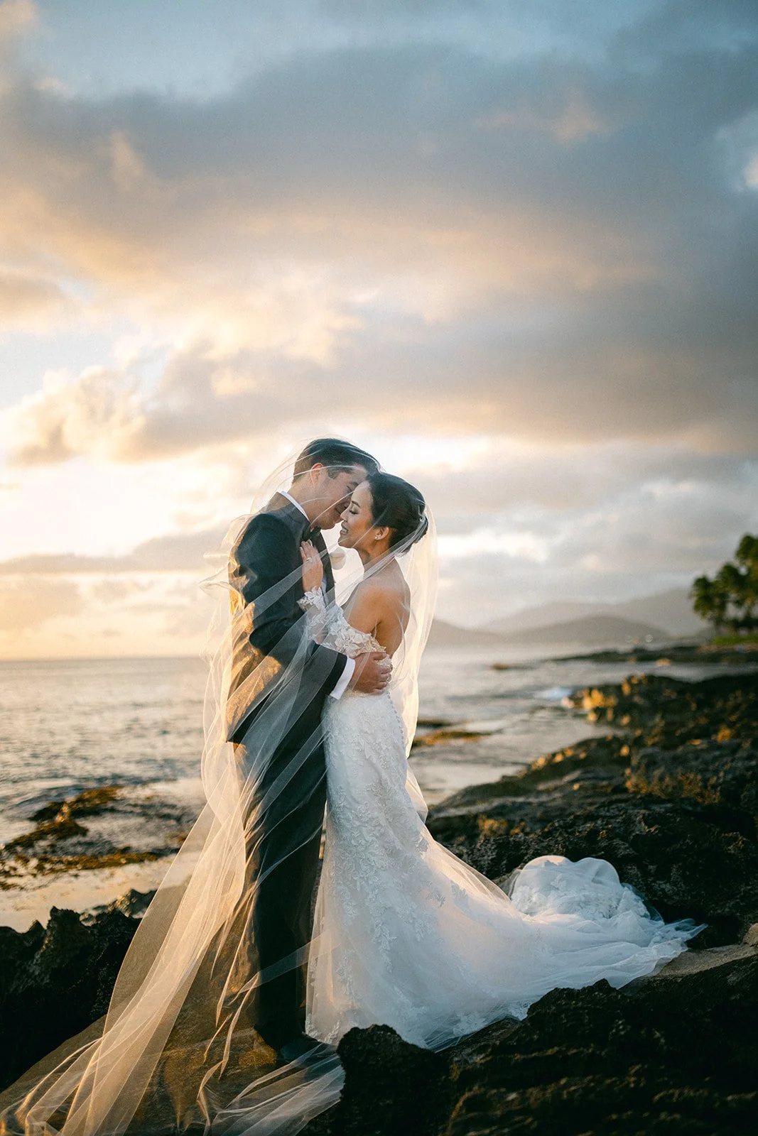 Couple posing at beach on rocks, featured in our elopement packages Hawaii