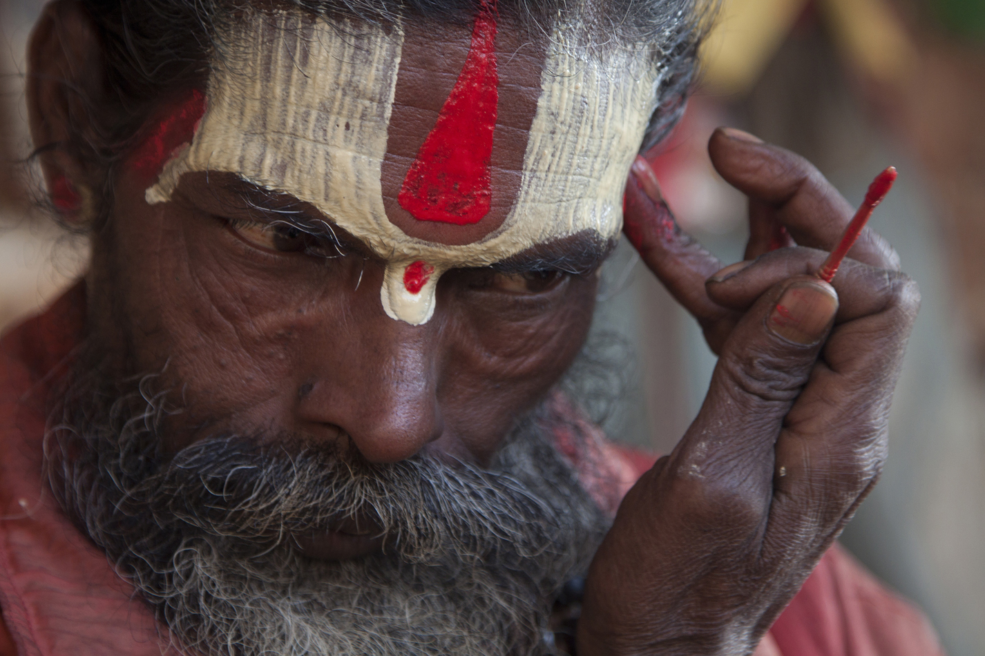  Nepal, a Sadhu near Pashupatinath temple. Painting his face before starting the day, daily ritual. 