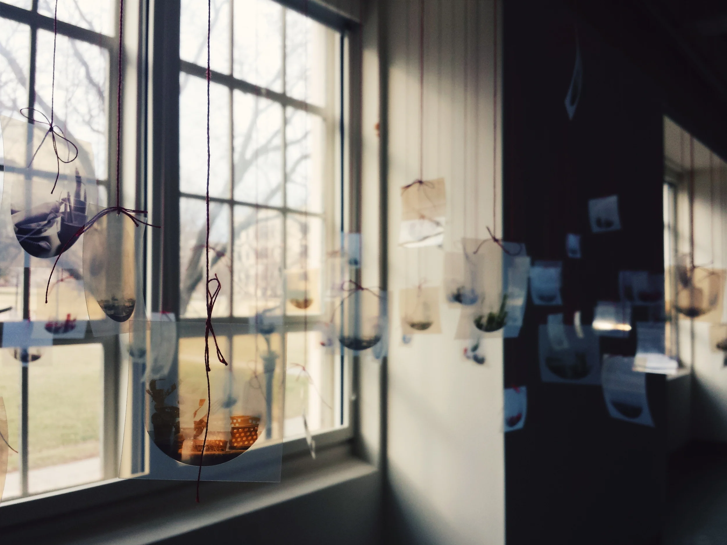 This is my favorite part of the entire show. It isn't a great photograph, but there are lots of tiny images hanging from red string in front of the window in the gallery. More details on this part of the installation to come. 