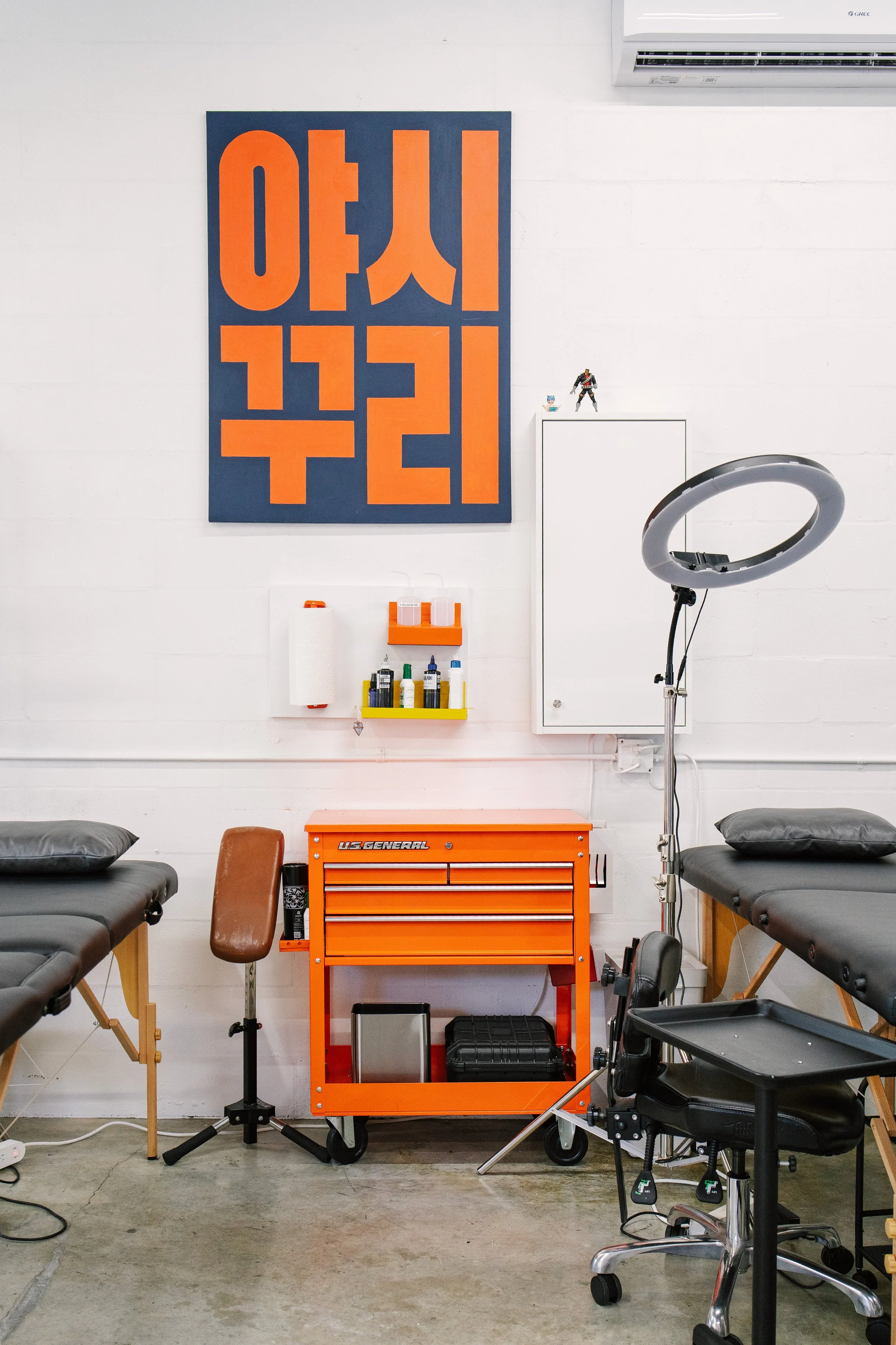 Tattoo artist workstation with an orange tool chest and a professional ring light.