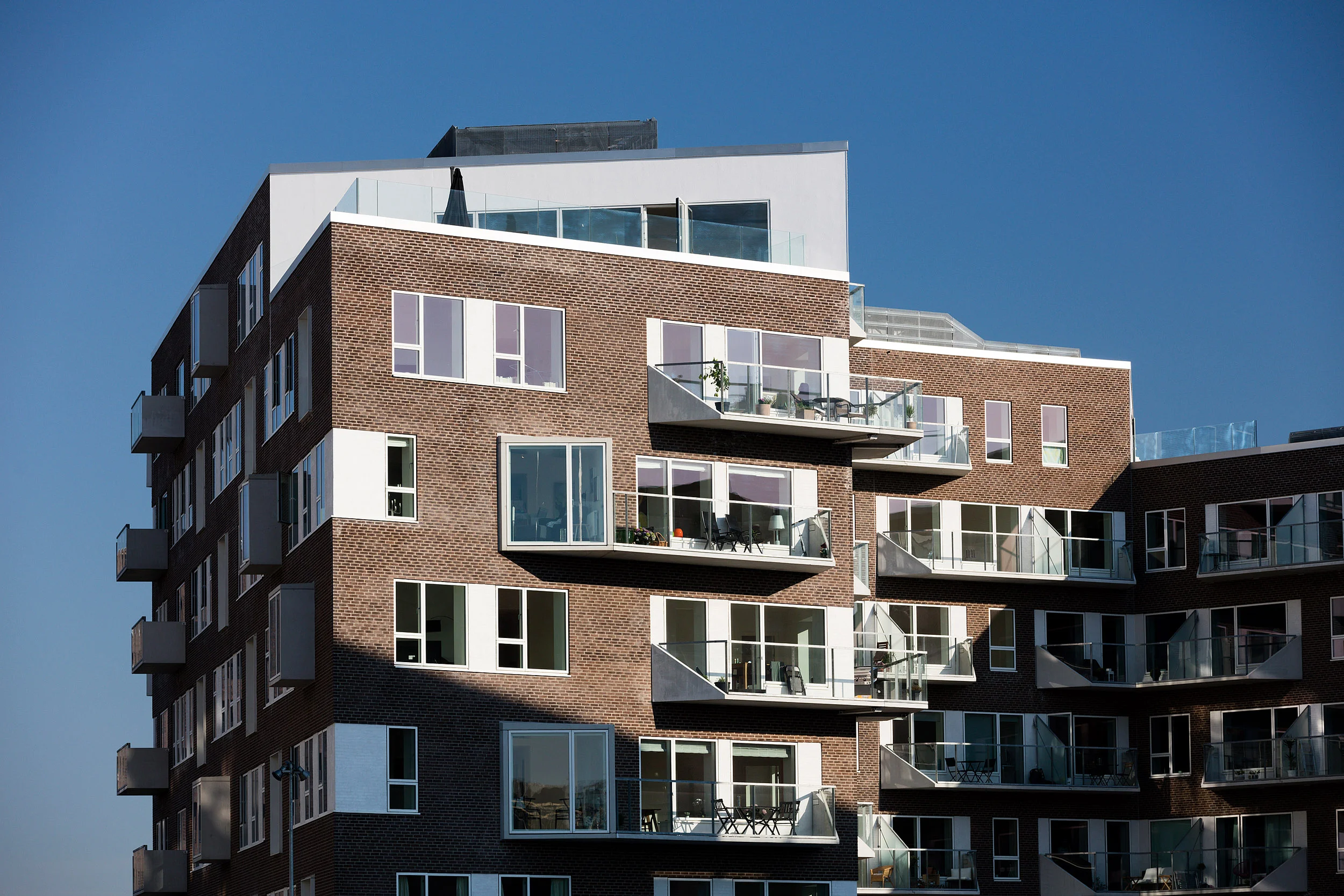 Residential housing, Skibbroen, realised by Holscher Nordberg Architects. Photographed from early morning throughout the day, letting the sun emphasise the various aspects of the buildings character. The special life that characterizes Skibbroen occurs due to users’ various activities and the mix of tranquility, activity, transit and practical doings.The uniqueness of the channel and harbor space is maintained. Photographed from early morning throughout the day, letting the sun emphasise the various aspects of the buildings character. 