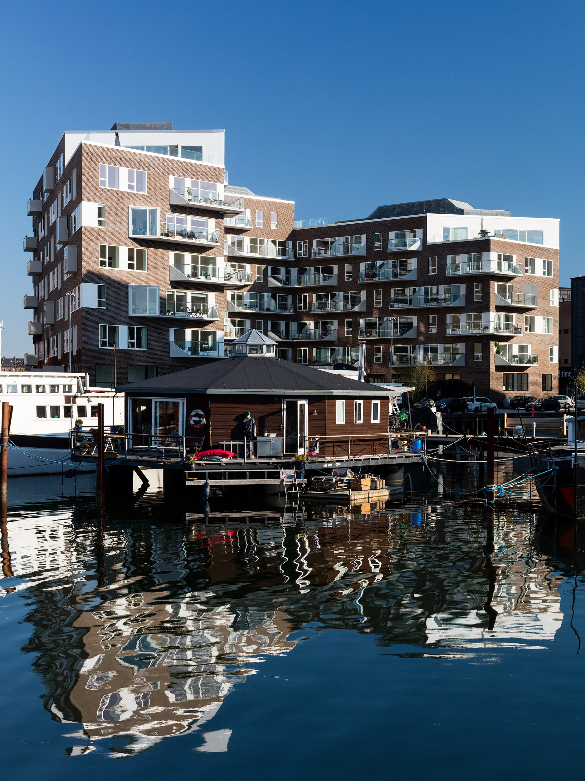 Residential housing, Skibbroen, realised by Holscher Nordberg Architects. Photographed from early morning throughout the day, letting the sun emphasise the various aspects of the buildings character. The special life that characterizes Skibbroen occurs due to users’ various activities and the mix of tranquility, activity, transit and practical doings.The uniqueness of the channel and harbor space is maintained. Photographed from early morning throughout the day, letting the sun emphasise the various aspects of the buildings character. 