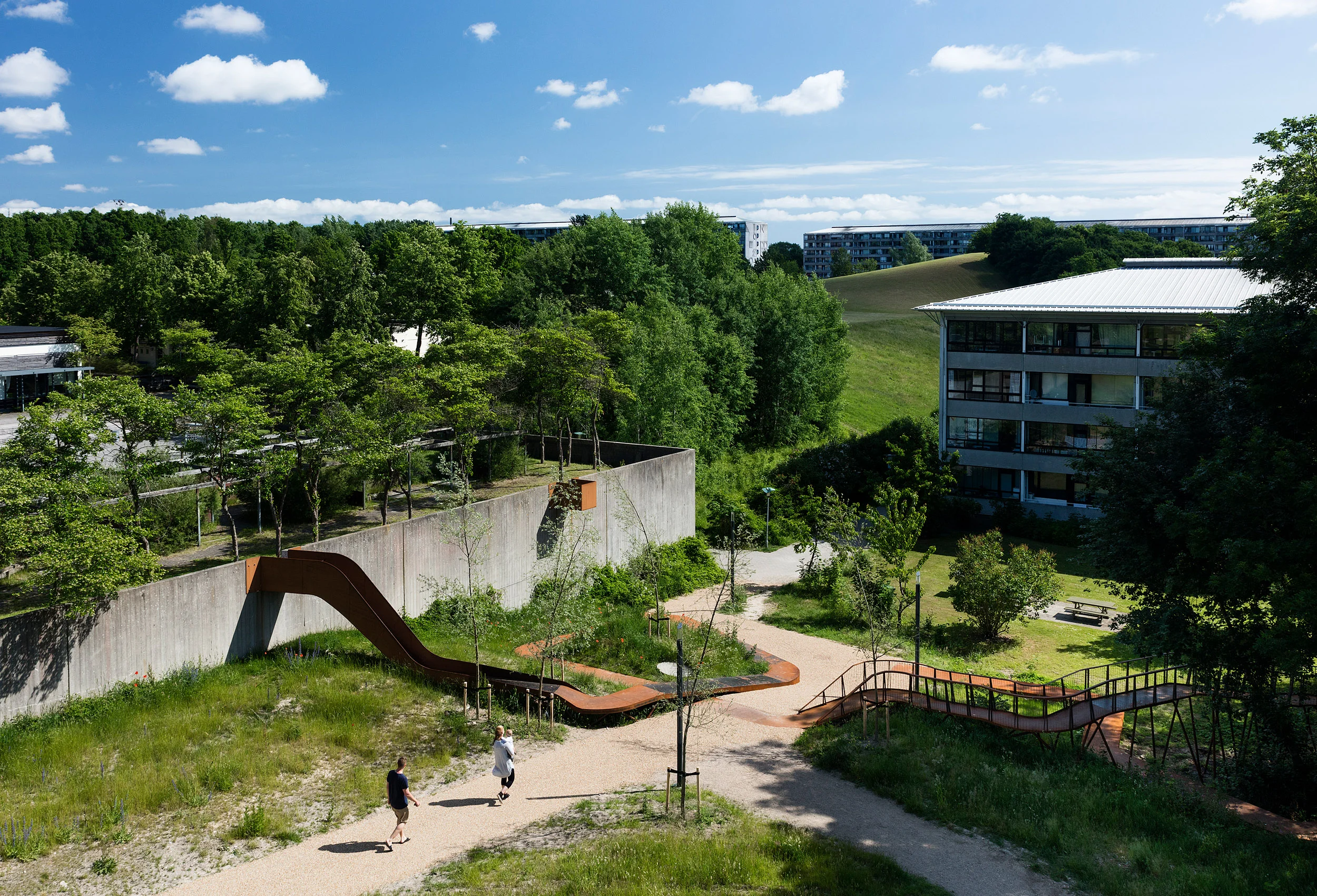 The Loop, realised by Holscher Nordberg Architects Værebro Park, a residential area in the suburbs of Copenhagen, has in the last years suffered from high crime rates and a declining number of inhabitants. Placed in the intersection between an indoor swimming pool, a primary and secondary school, and the 1400 dwellings of Værebro Park, the activity path aims to create a physical and mental bridge between the different users of the area. The low budget yet esthetical element is designed as a playful path offering a variation of activities.