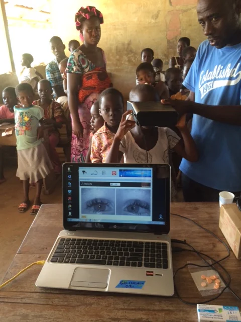 Patients are enrolled using a picture of their eyes. The system is easy to use and portable. This photos shows parent volunteers helping with malaria screening in their children's school.