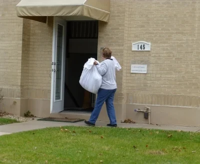 Volunteer and Board Member Lynn Harlan carries textiles into the new location to be hung up.
