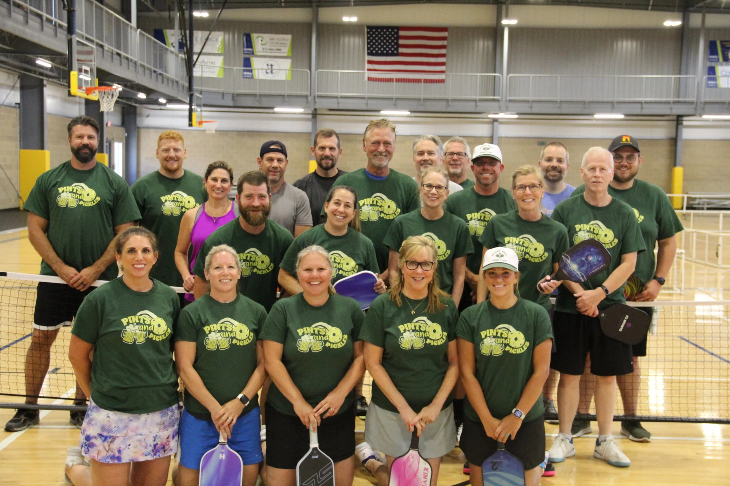 A group of adults pose for a group picture with their pickleball gear.