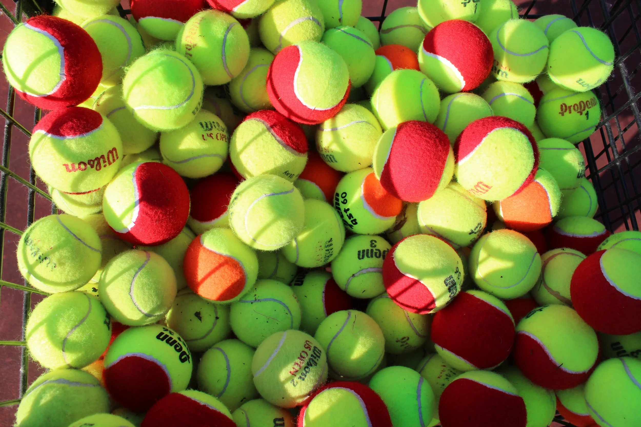 A picture of a giant basket of yellow and red tennis balls.
