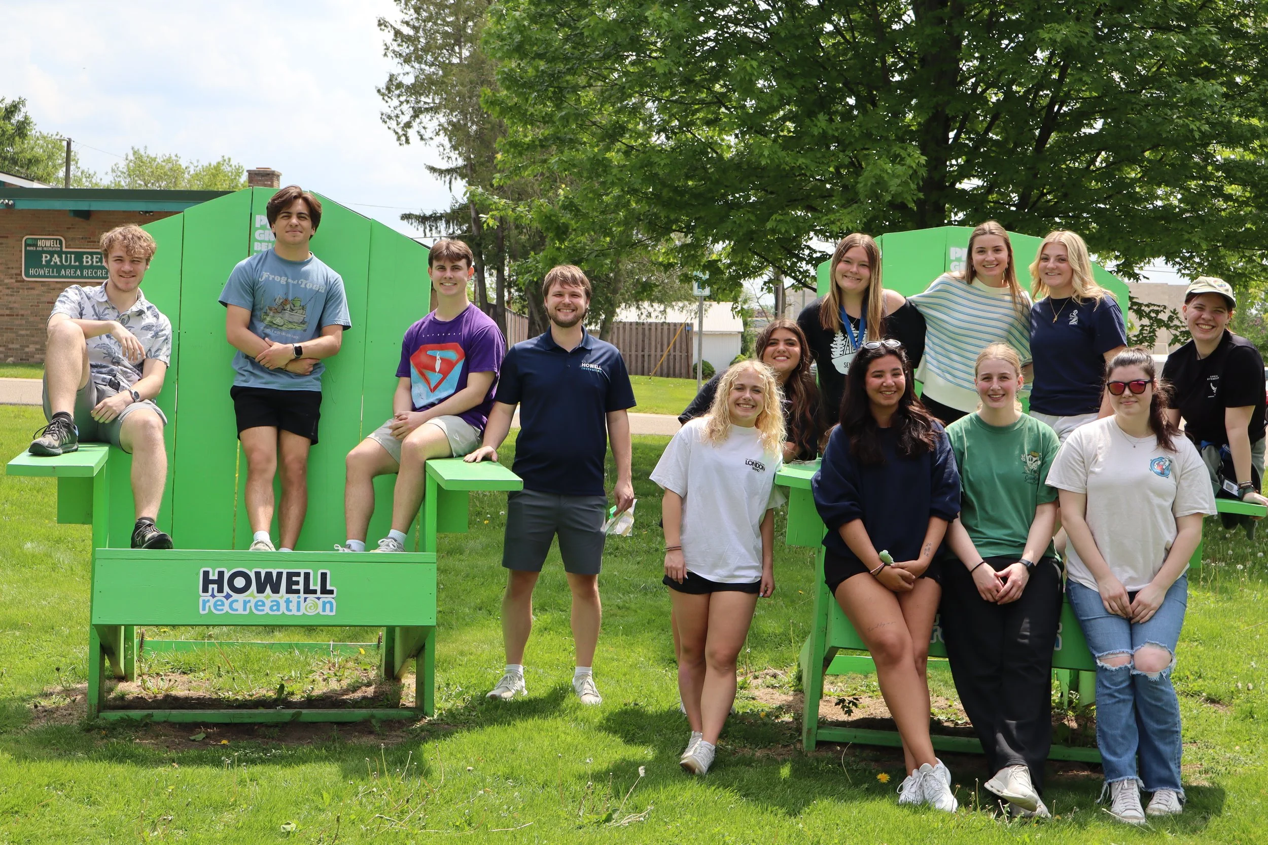 A photo of a group of Howell Recreation staff posing in front of a giant green chair.