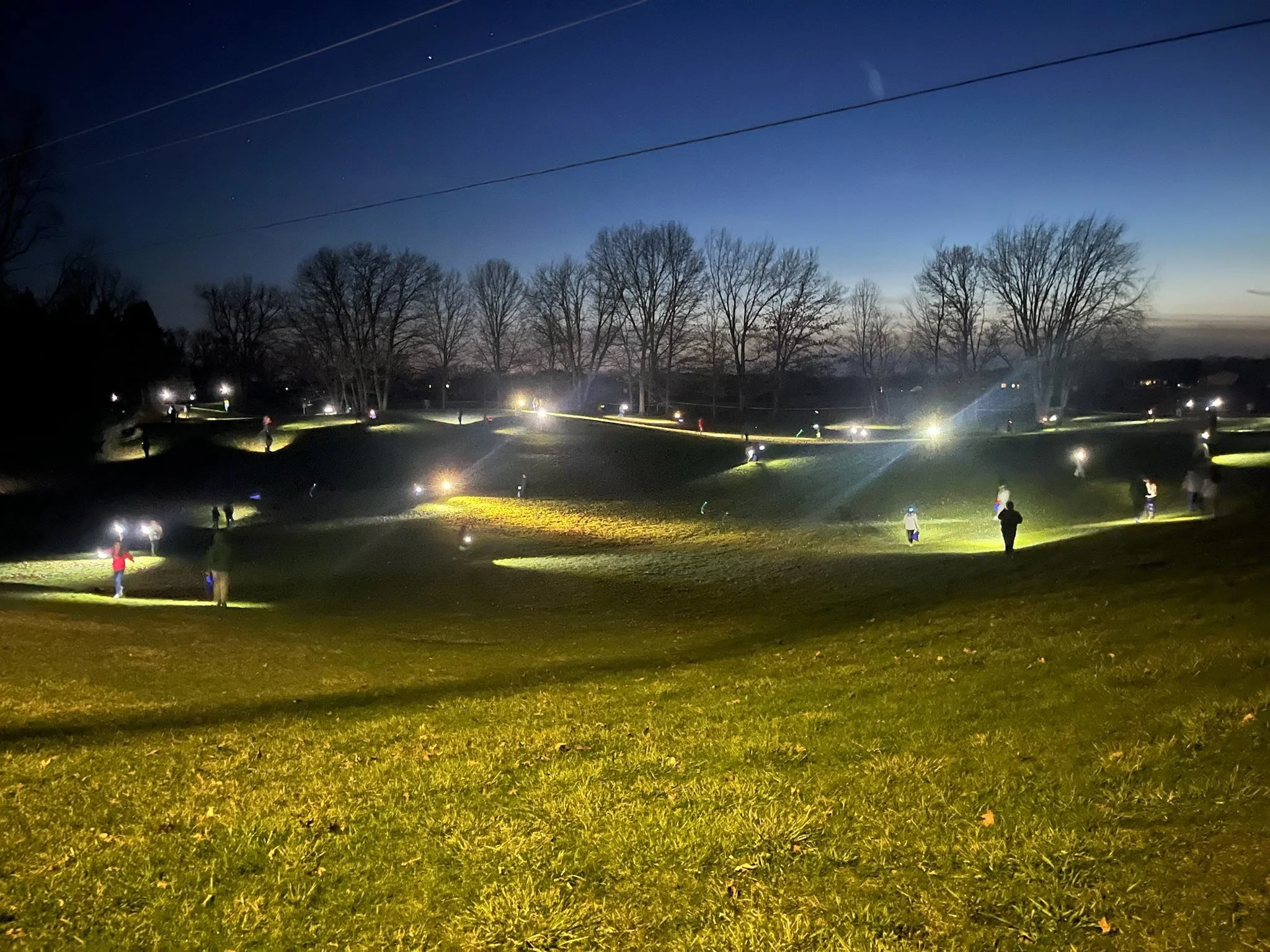 A group of teens search for easter eggs with flashlights in a hilly area.