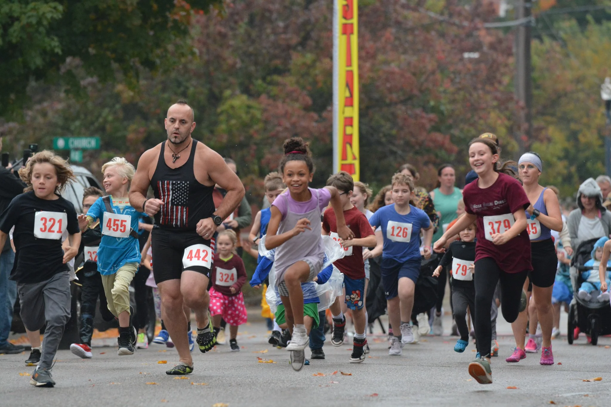 A photo of a group of smiling runners dash forward at the Headless Horseman 5K.