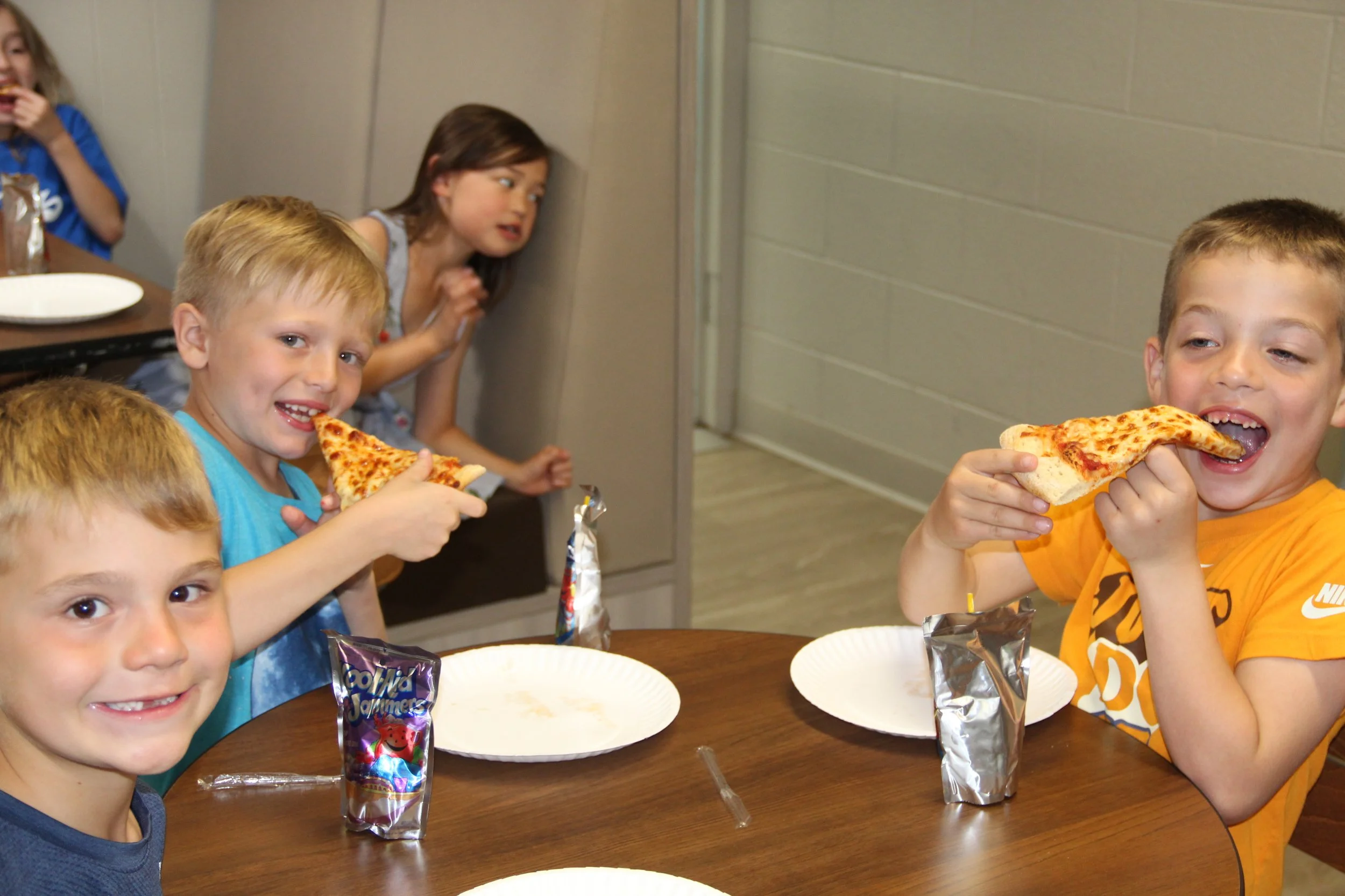 A group of kids eat pizza at a kids night out event.
