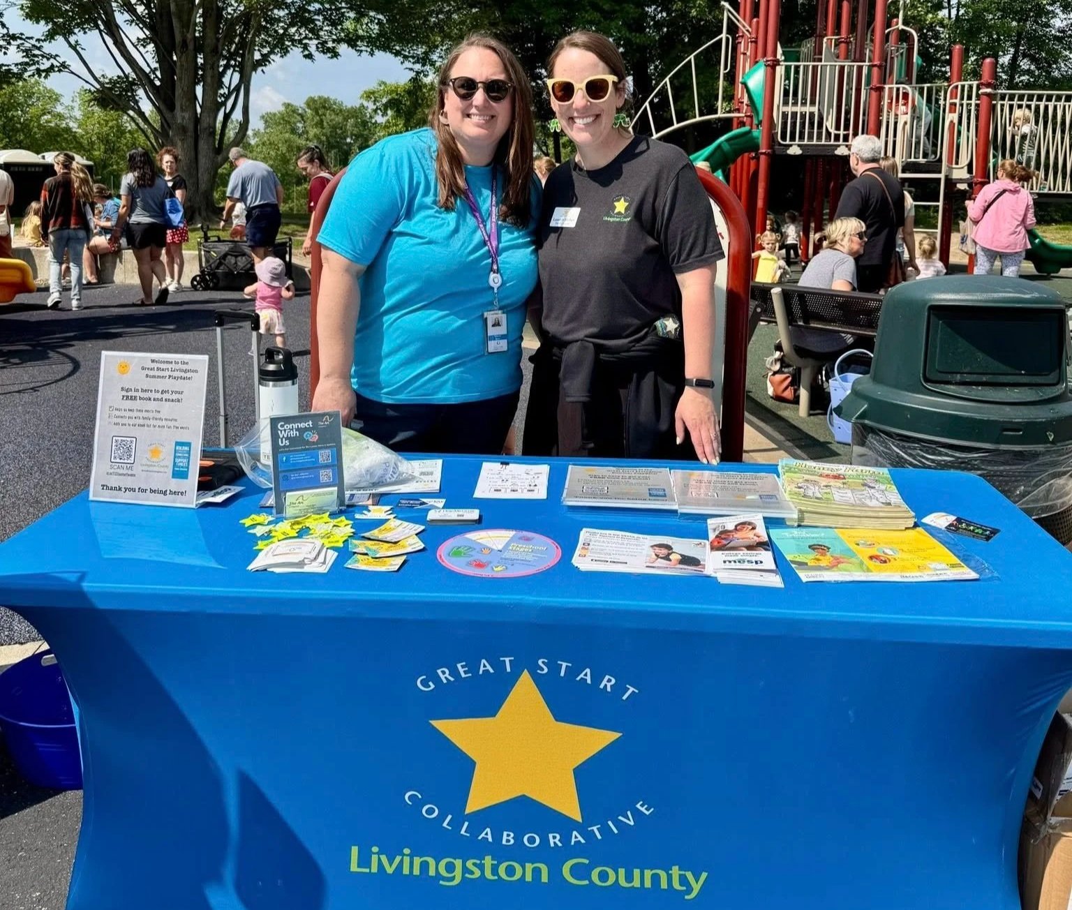 Two woman stand at a booth for Great Start Livingston.
