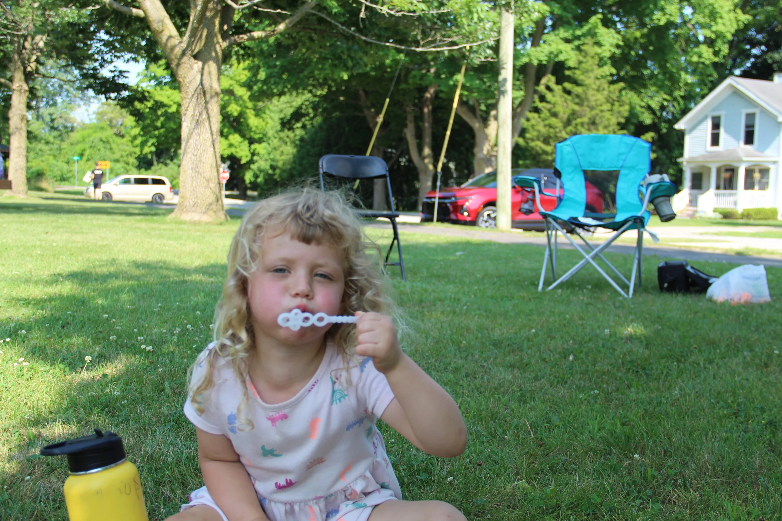 A little girls blows bubbles with a bubble wand.