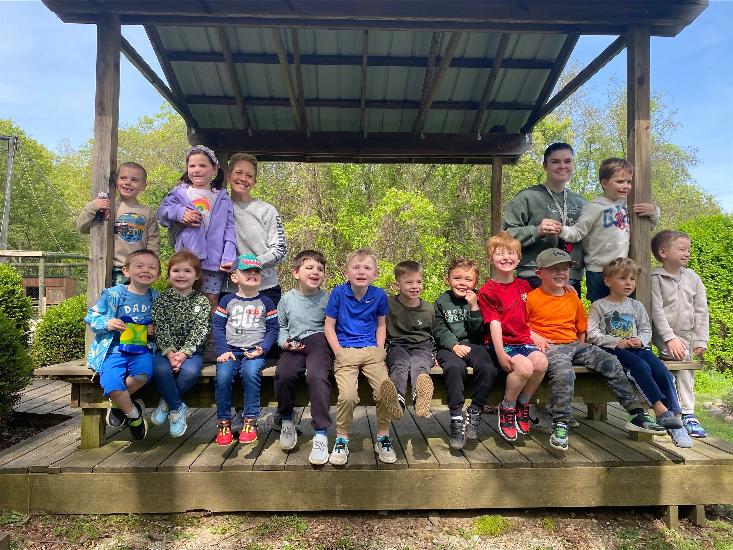A photo of the preschool class smiling at an outdoor gazebo .